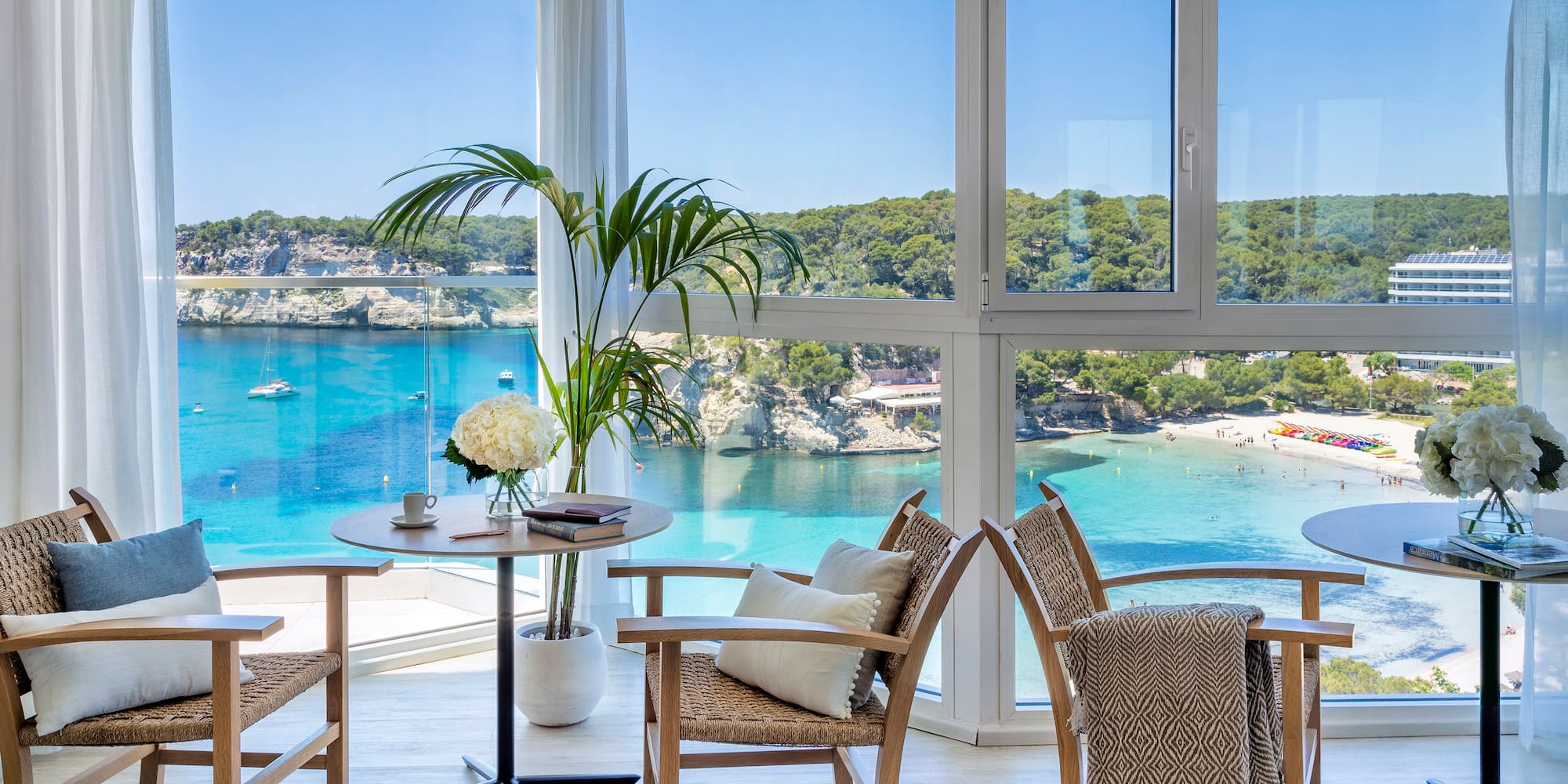 a room with a view of the ocean and a table and chairs