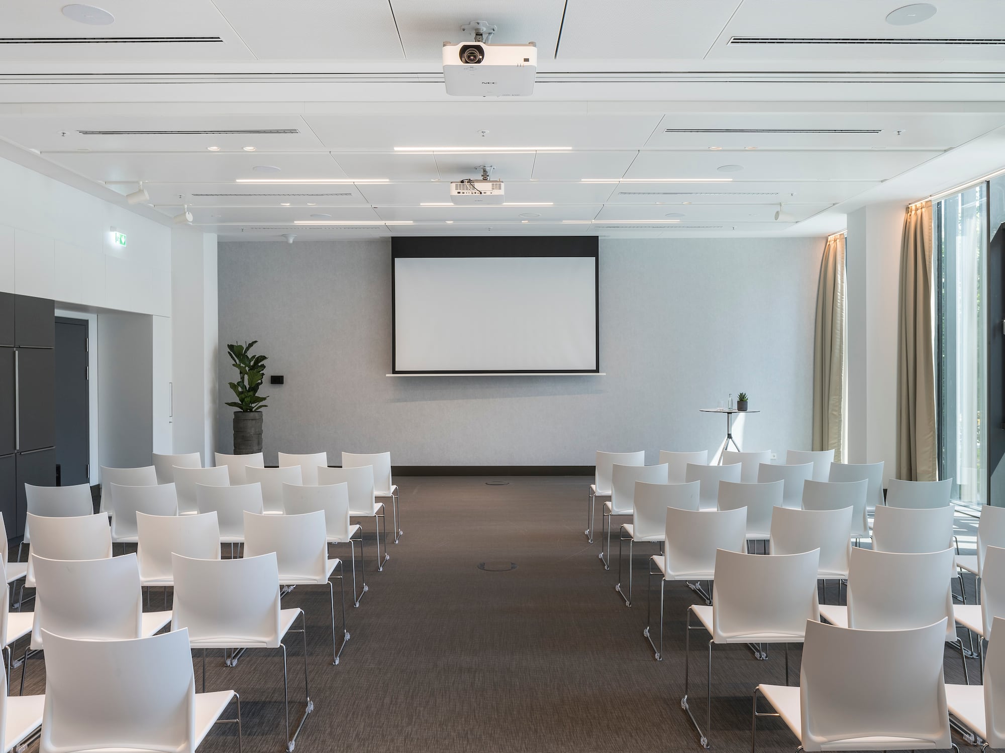 a room with white chairs and a projector screen