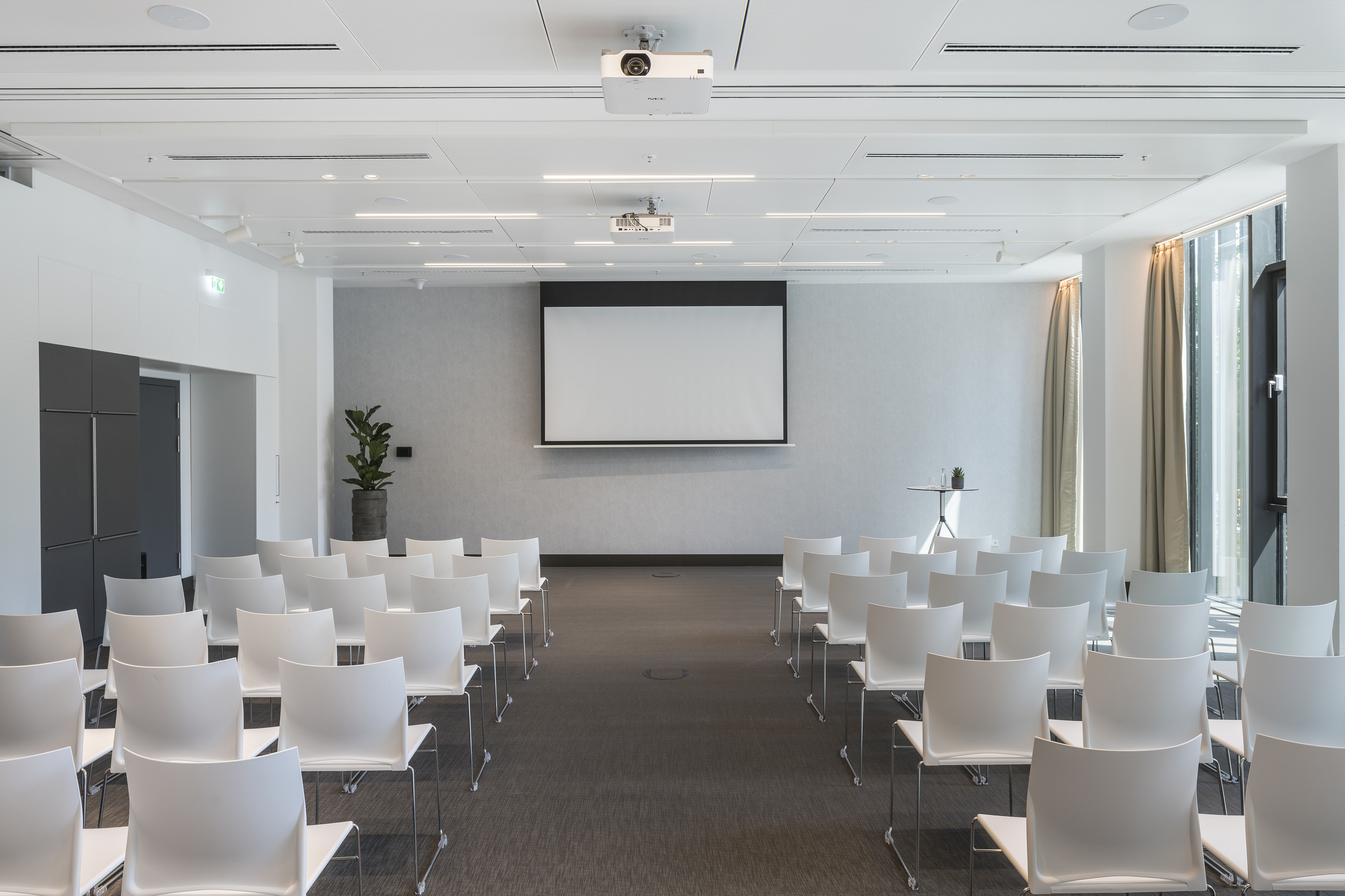 Modern conference room with white chairs and projector screen.