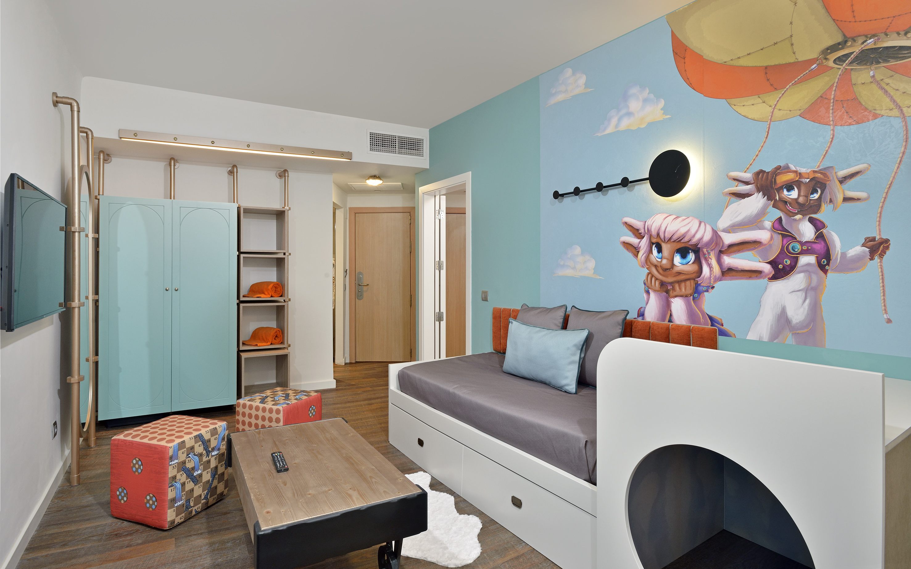 Cartoon-themed kids hotel room with wall mural, daybed, and playful modern decor.