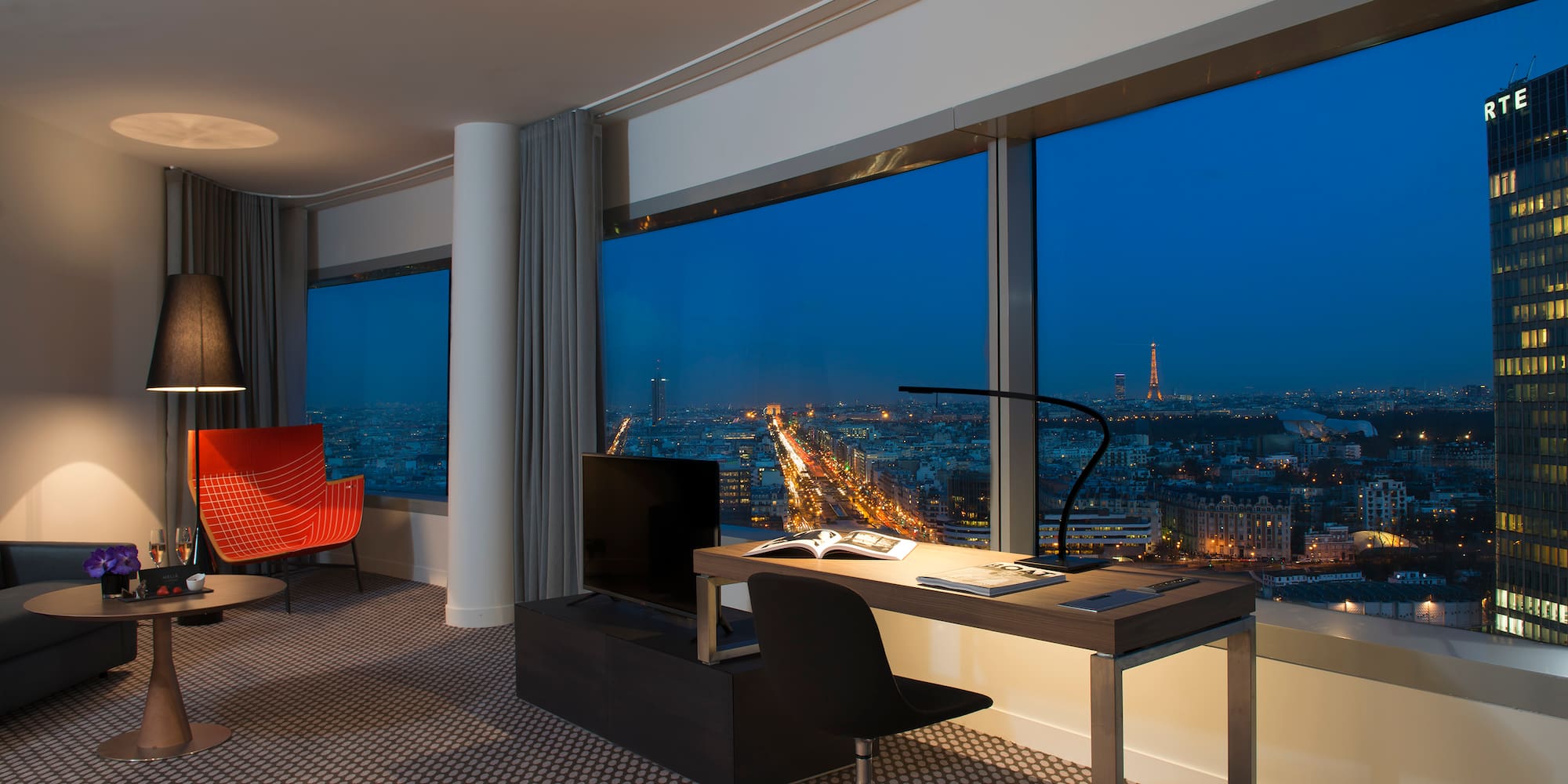 a room with a large window and a desk and chairs