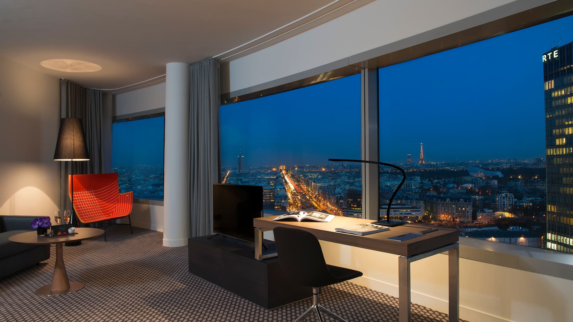 a room with a large window and a desk and chairs