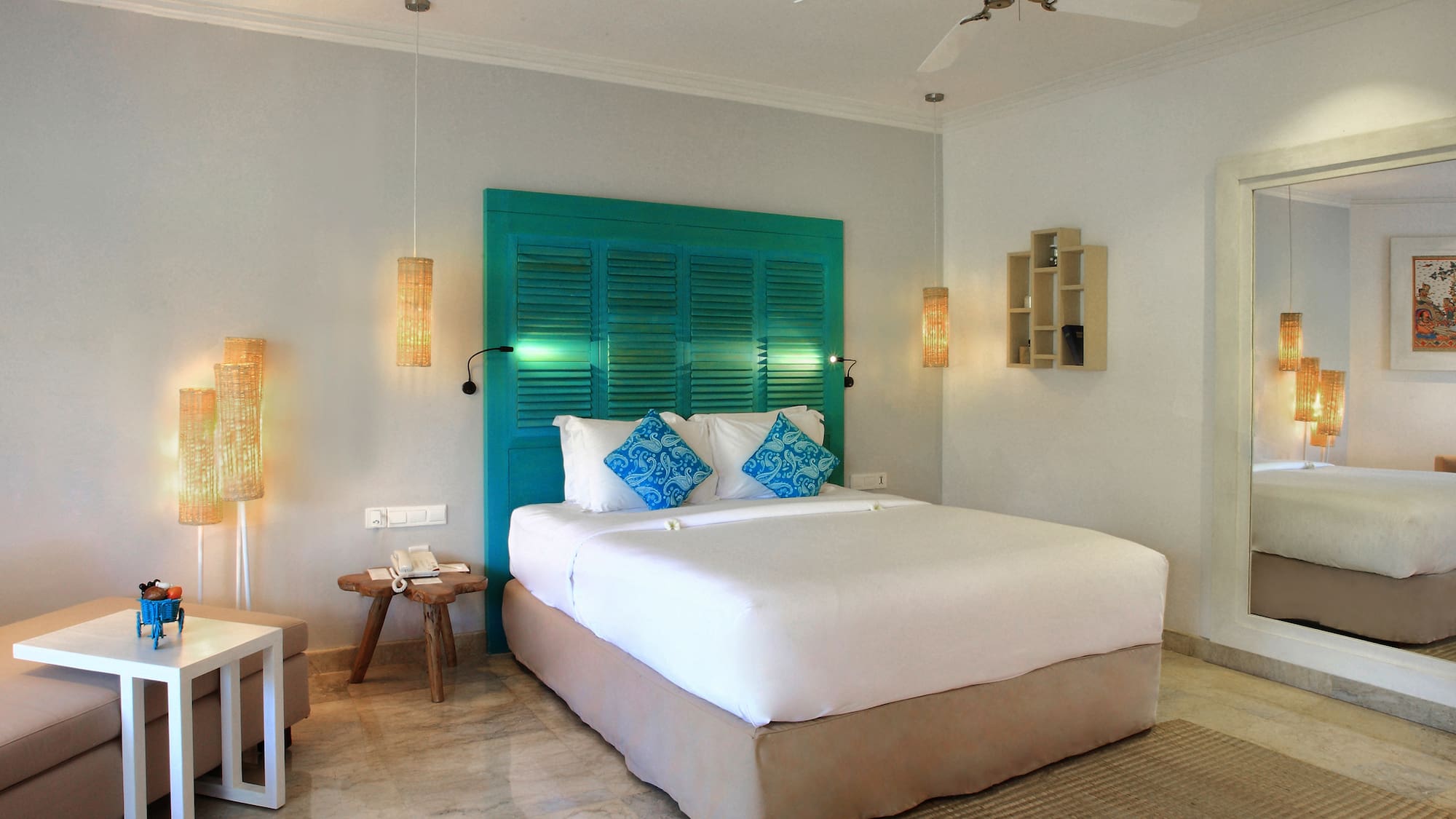 a bed with blue pillows and a fan in a room