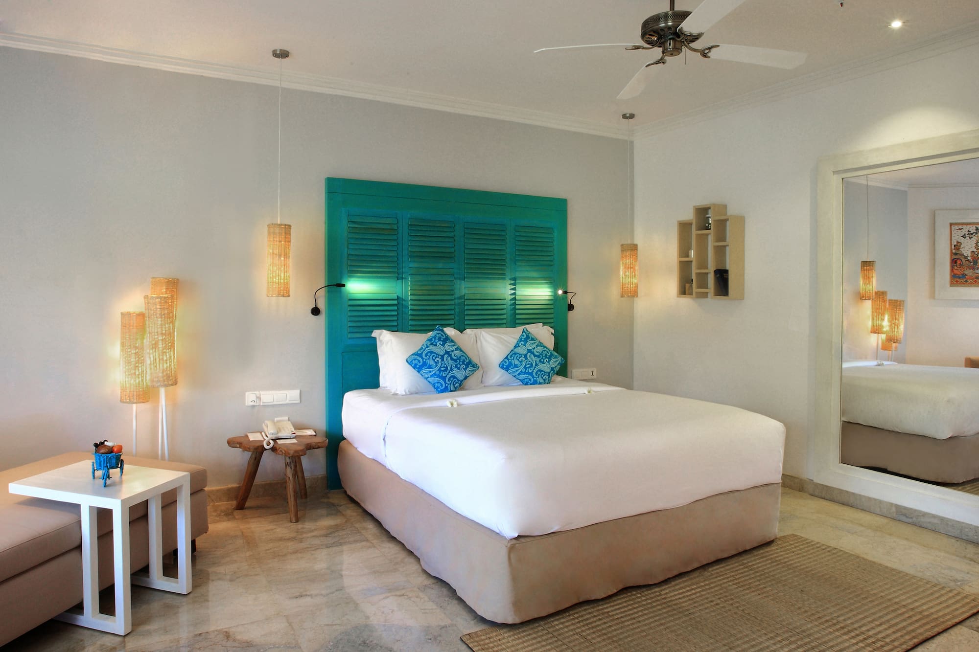 a bed with blue pillows and a fan in a room