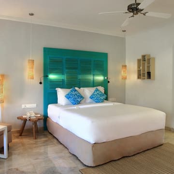 a bed with blue pillows and a fan in a room