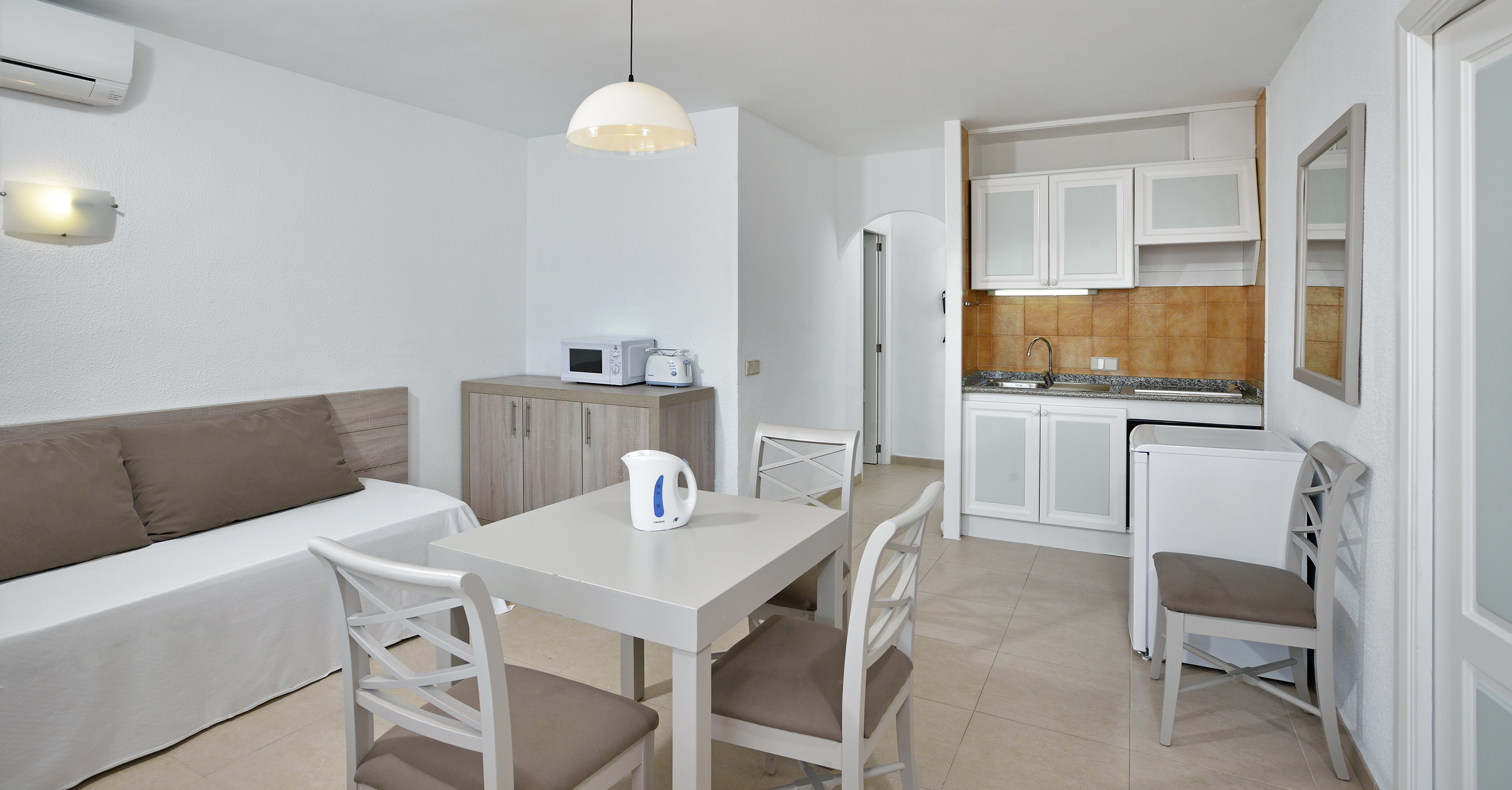 Modern studio apartment with kitchenette, dining table, and sofa bed.