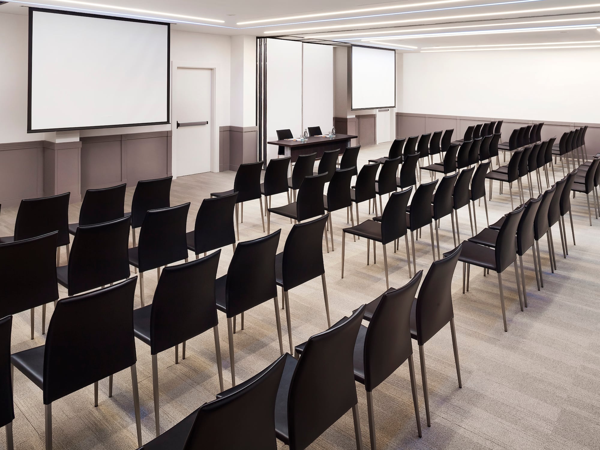 a room with black chairs and a projector screen