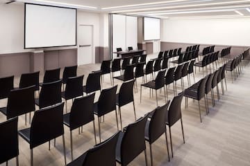 a room with black chairs and a projector screen