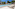 Resort swimming pool with sun loungers, palm trees, and outdoor seating area.