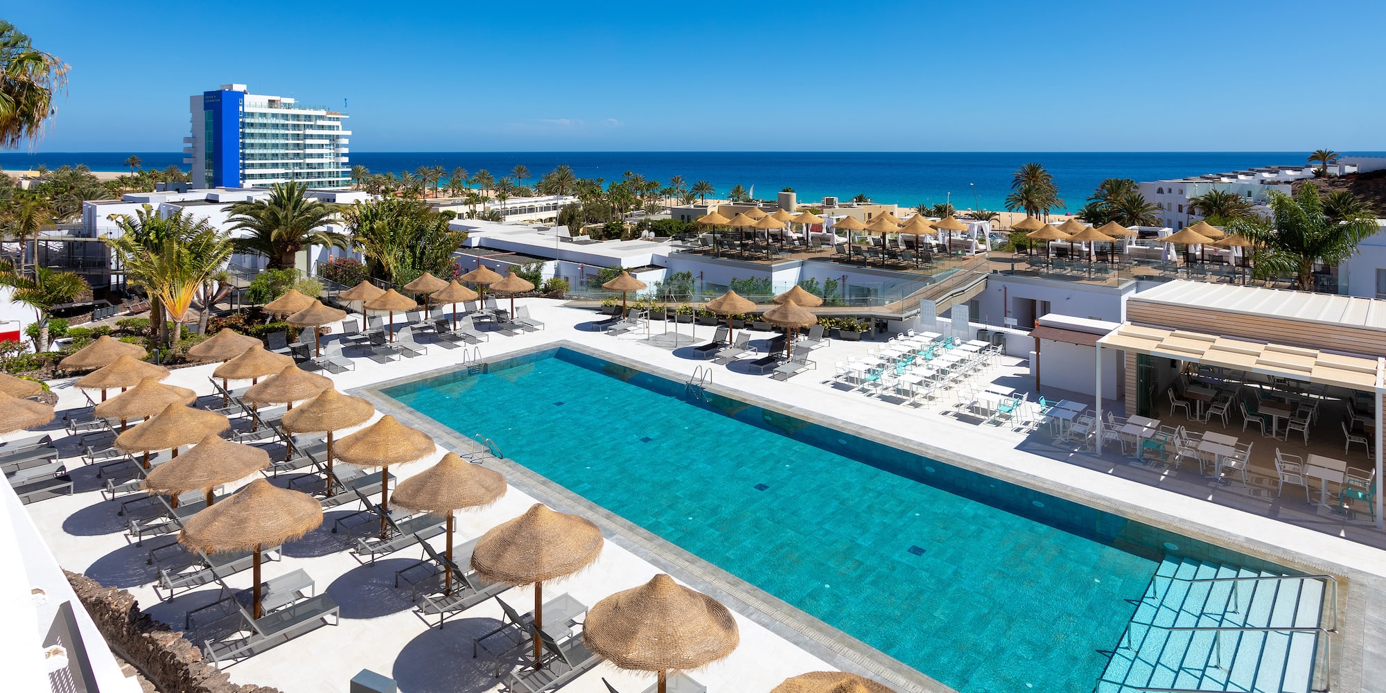 a swimming pool with umbrellas and chairs and a building with a body of water