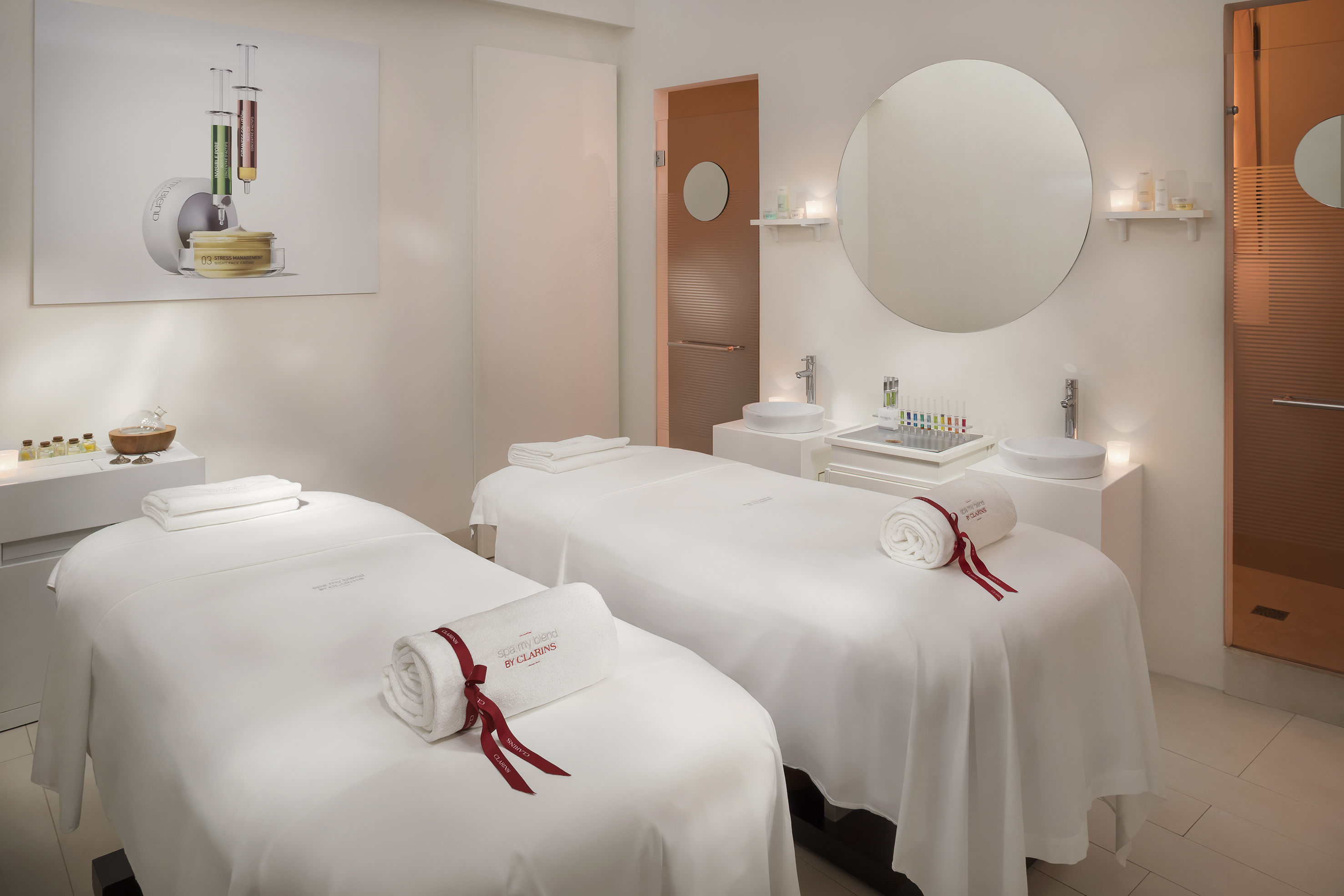 Luxurious Clarins spa treatment room with two massage beds and skincare products.