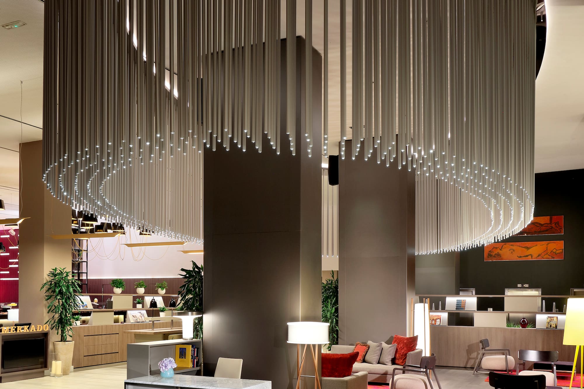Modern hotel lobby with circular light fixture, reception desk, and lounge seating.