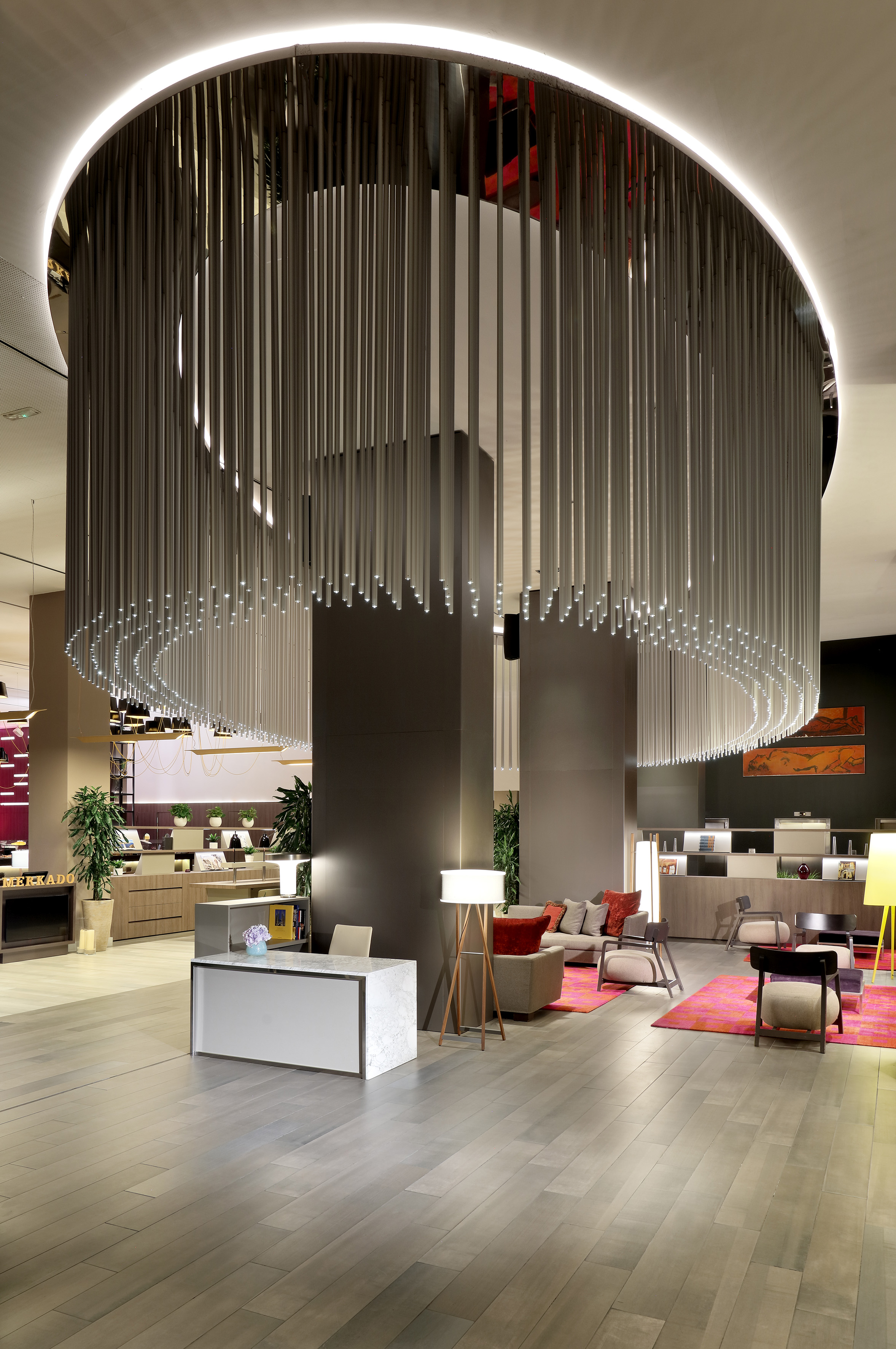 Modern hotel lobby with circular light fixture, reception desk, and lounge seating.