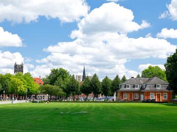 A green lawn framed by buildings and trees in the distance.