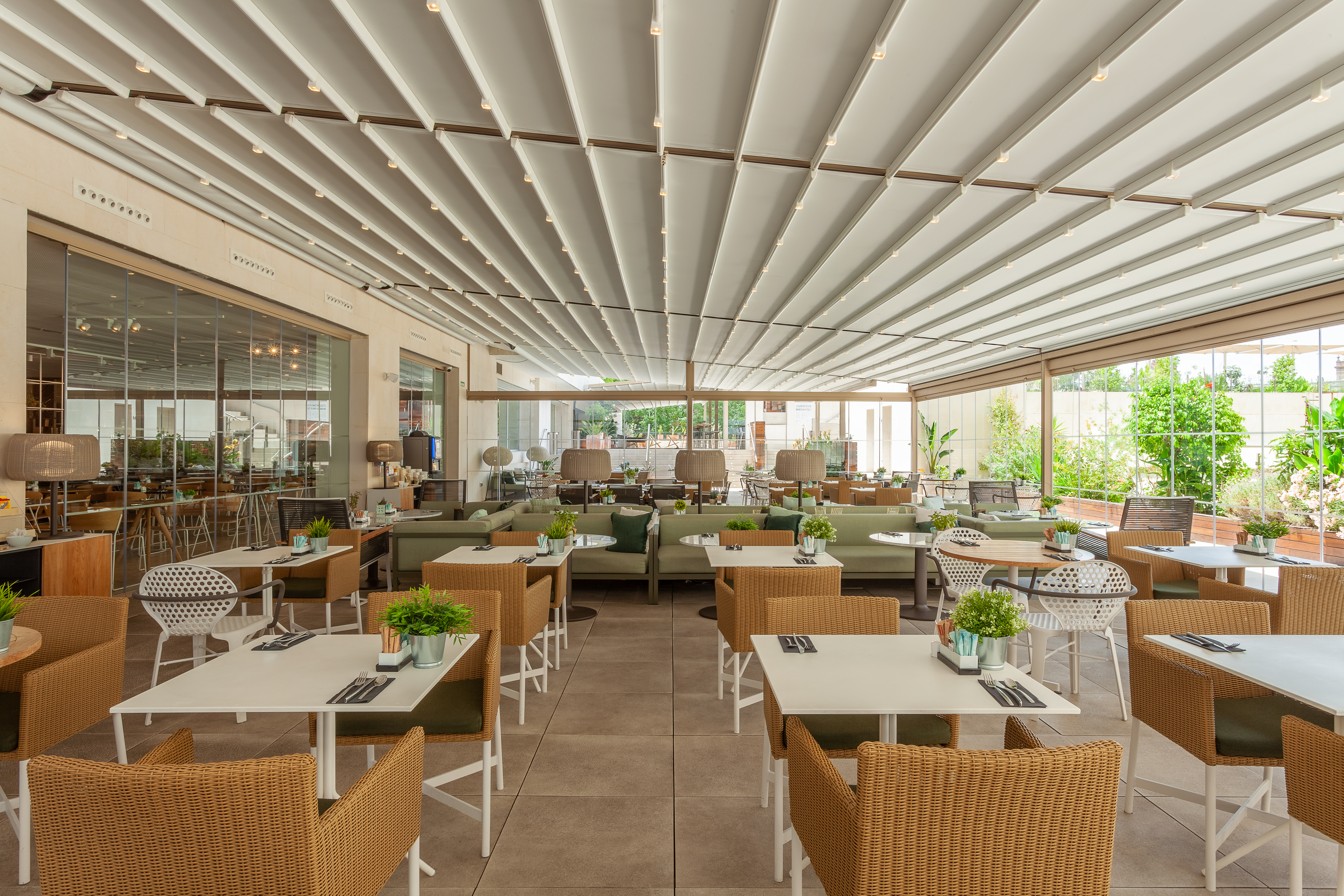 Outdoor restaurant patio with retractable roof and modern wicker seating.