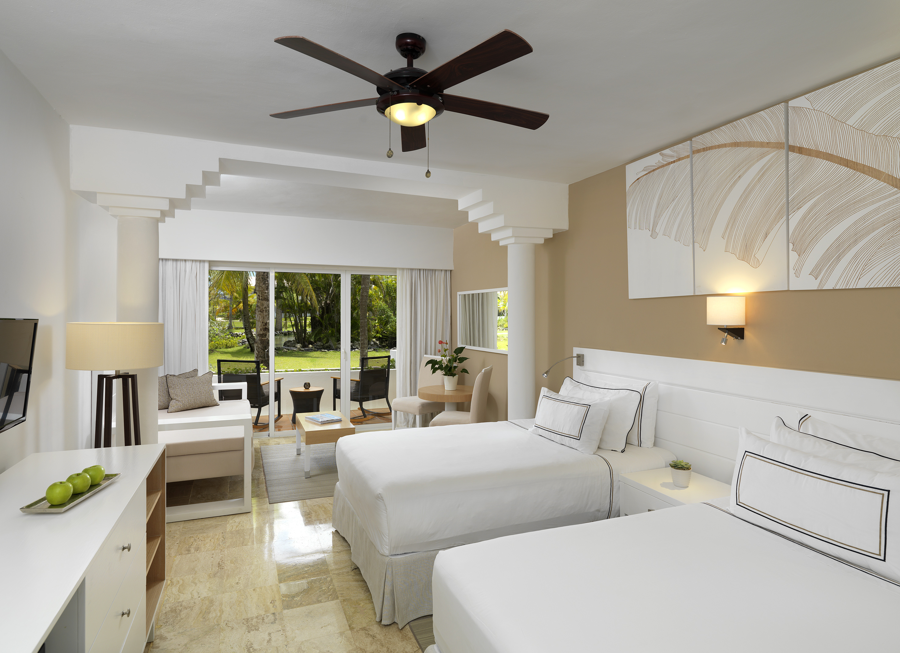 Tropical hotel room with two beds, ceiling fan, and garden view balcony.