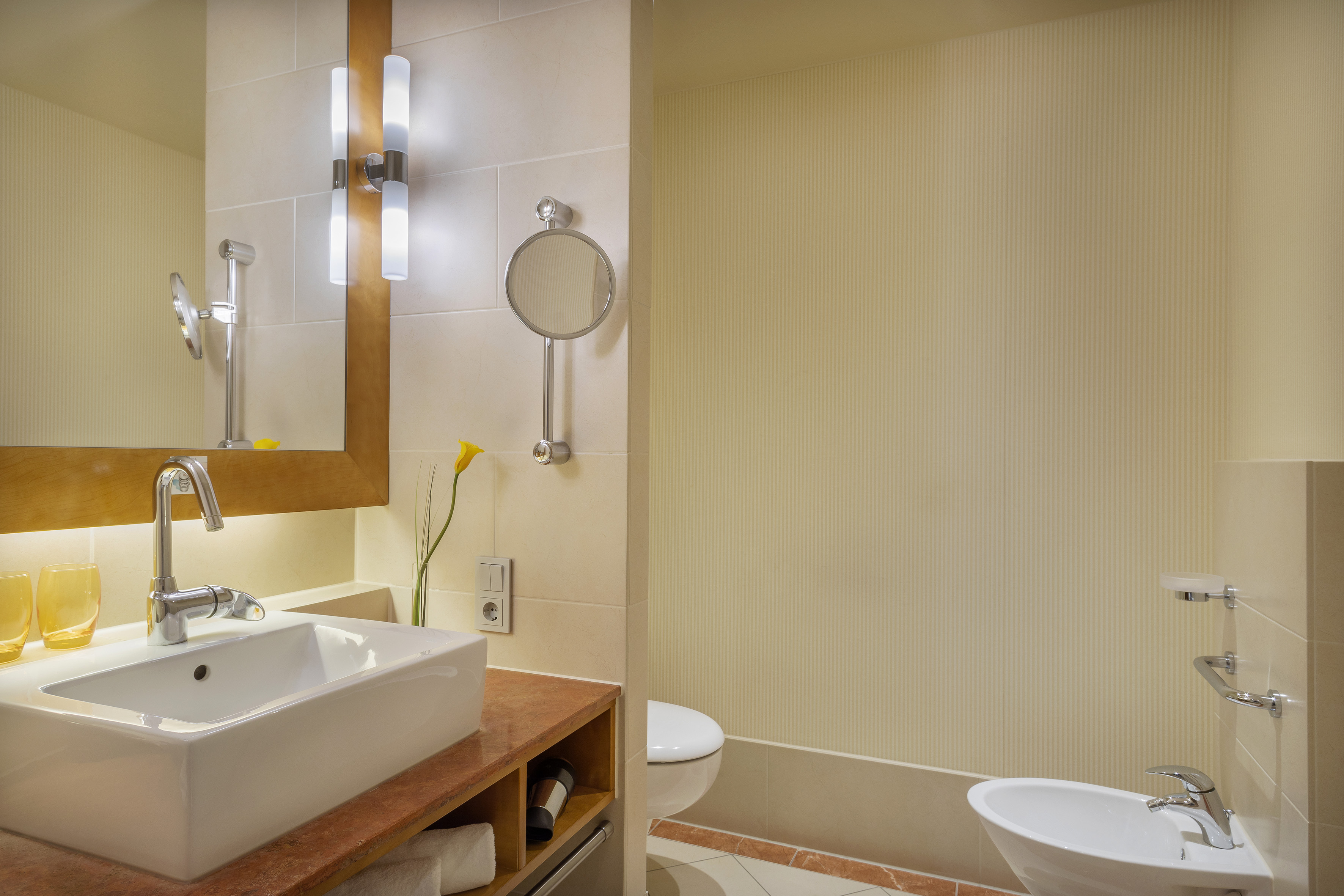 Modern bathroom with rectangular sink, mirror, toilet, and bidet.
