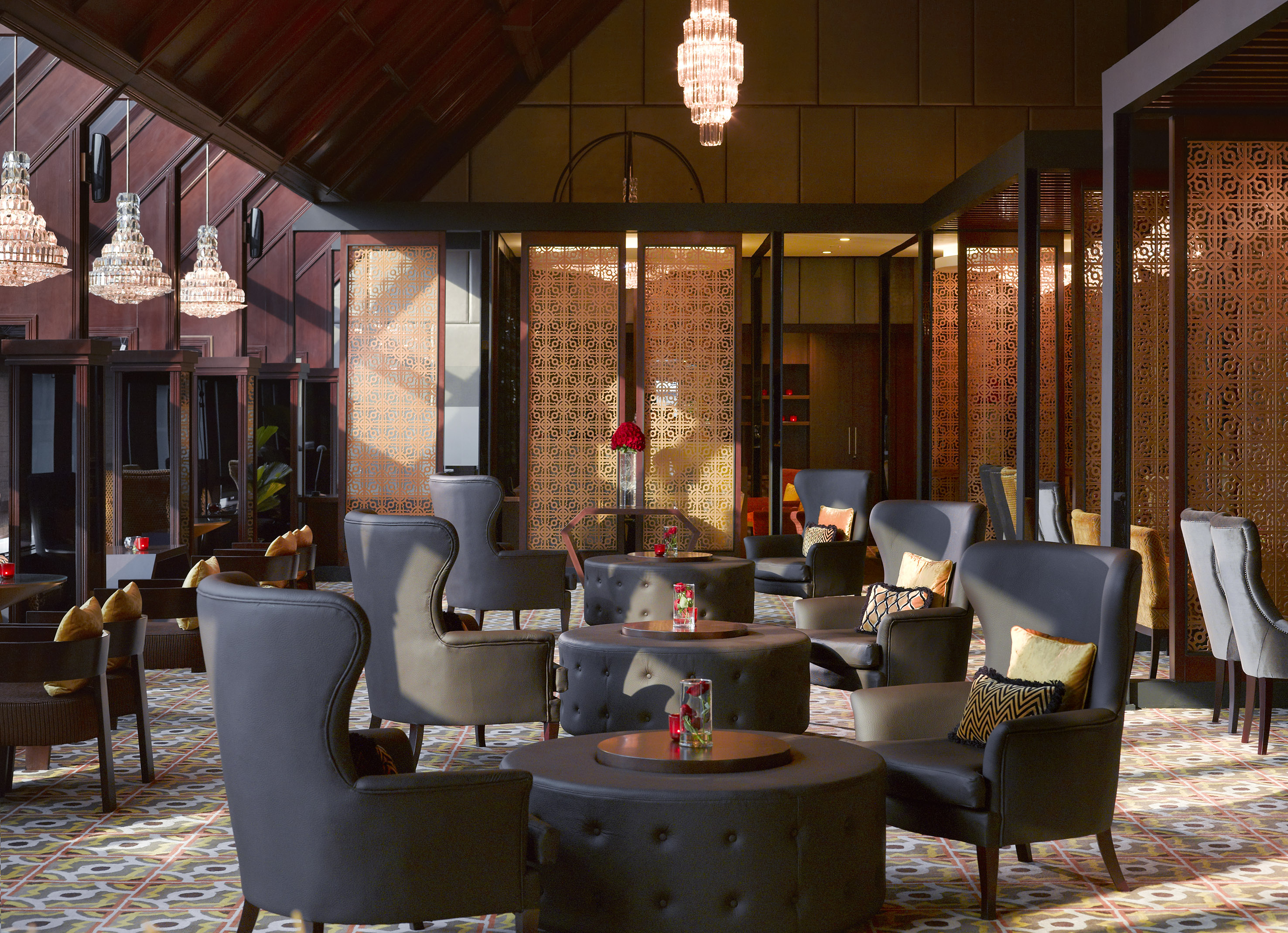 Elegant hotel lounge, dark seating, patterned floor, crystal chandeliers.