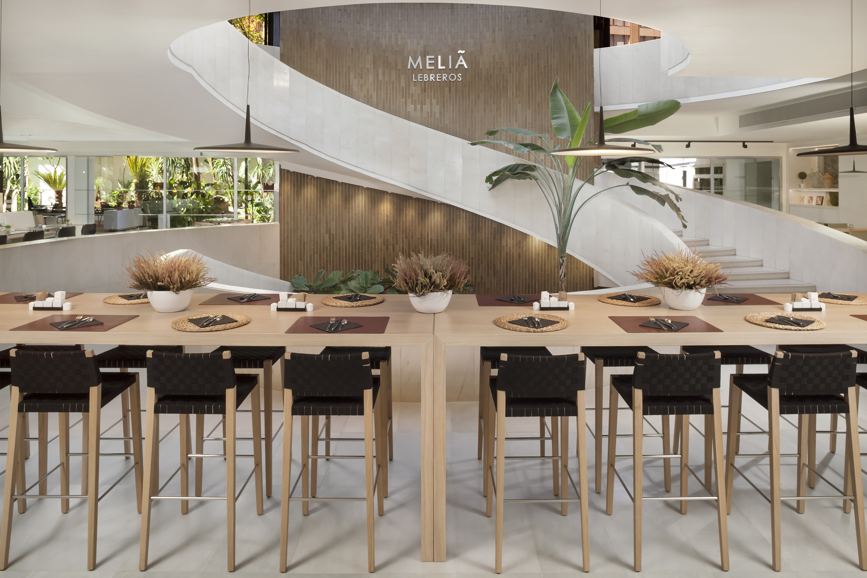 Meliá Lebreos hotel dining with communal table, spiral staircase, modern design.