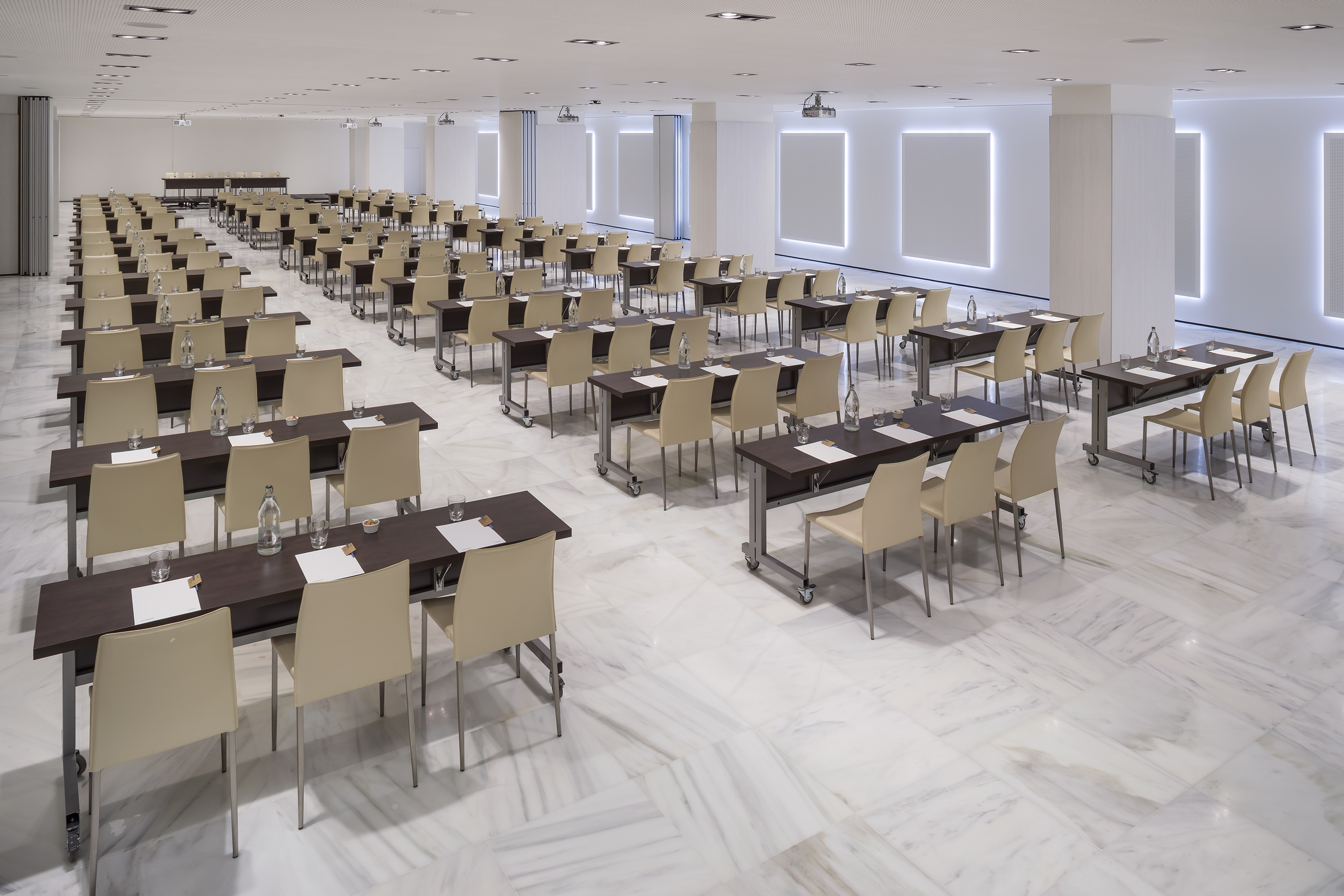 Spacious meeting room with dark tables, beige chairs, and elegant marble floor.