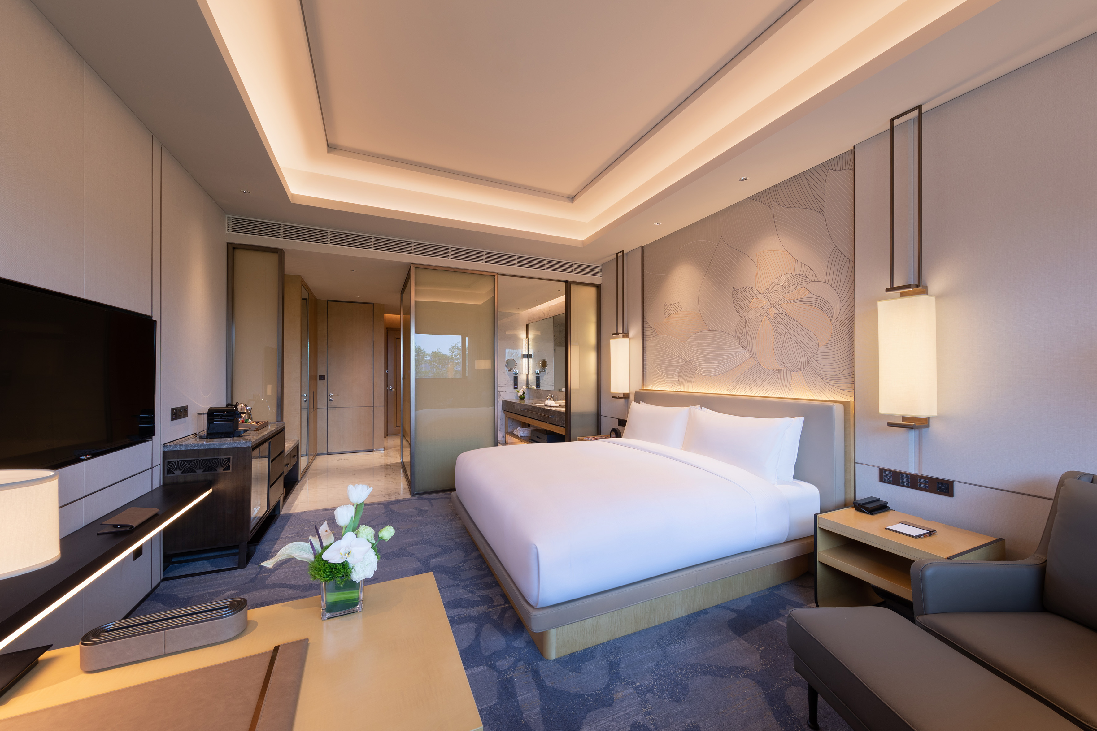 Modern luxury hotel room with king bed, TV, and elegant bathroom access.