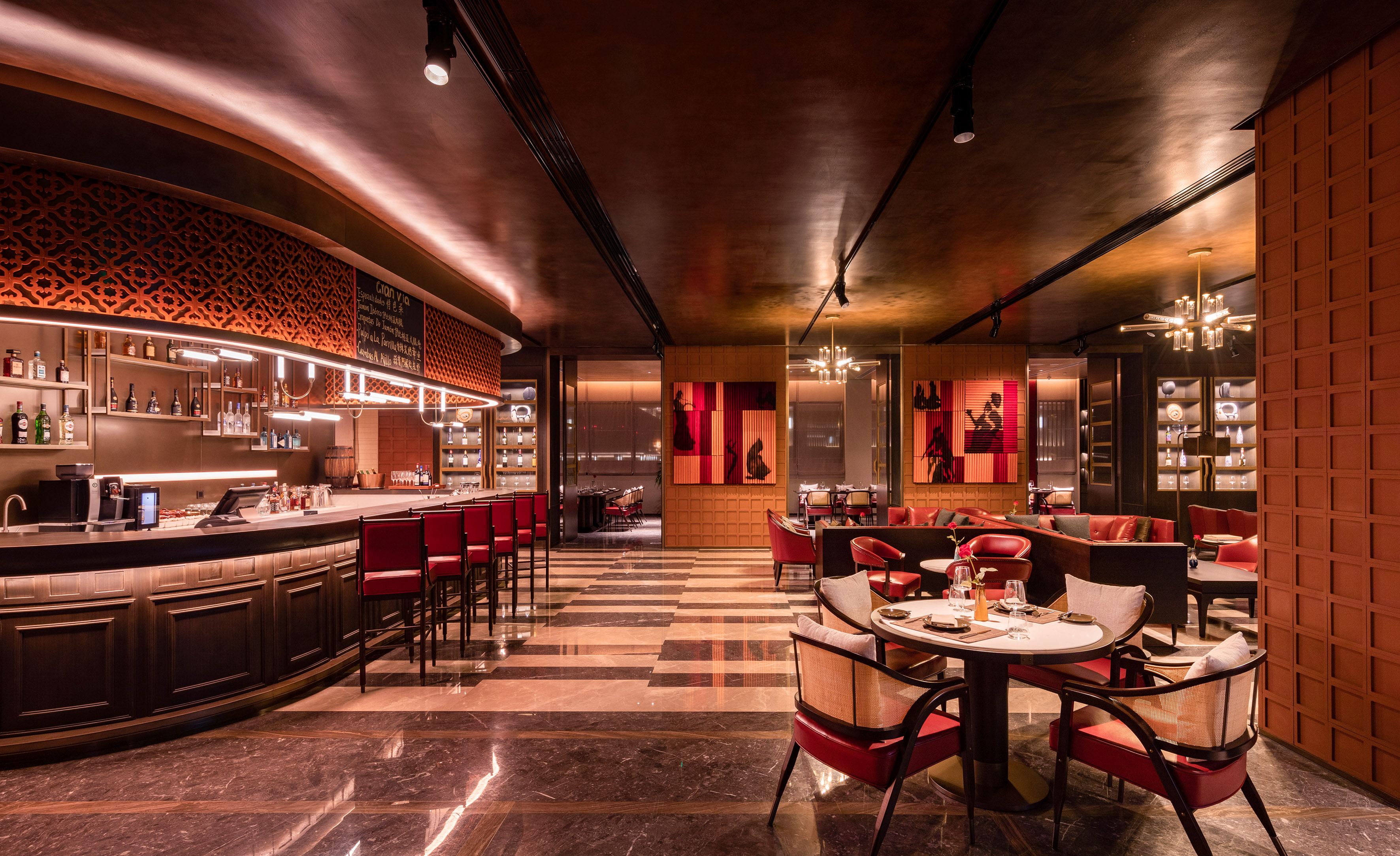 Elegant bar and restaurant interior with red chairs, dark wood, and marble floor.