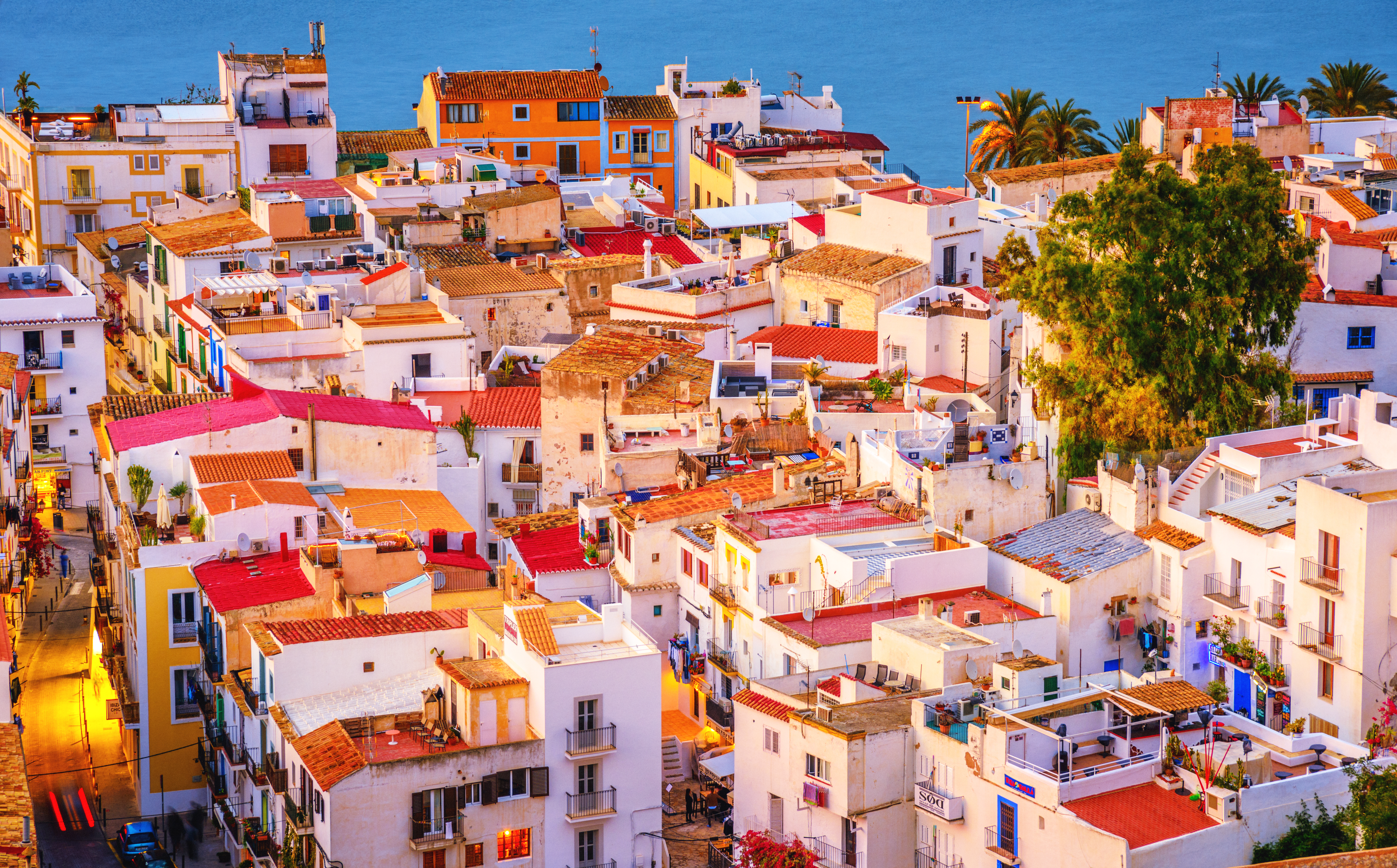 Coastal Mediterranean town with whitewashed buildings, red roofs, and blue sea.