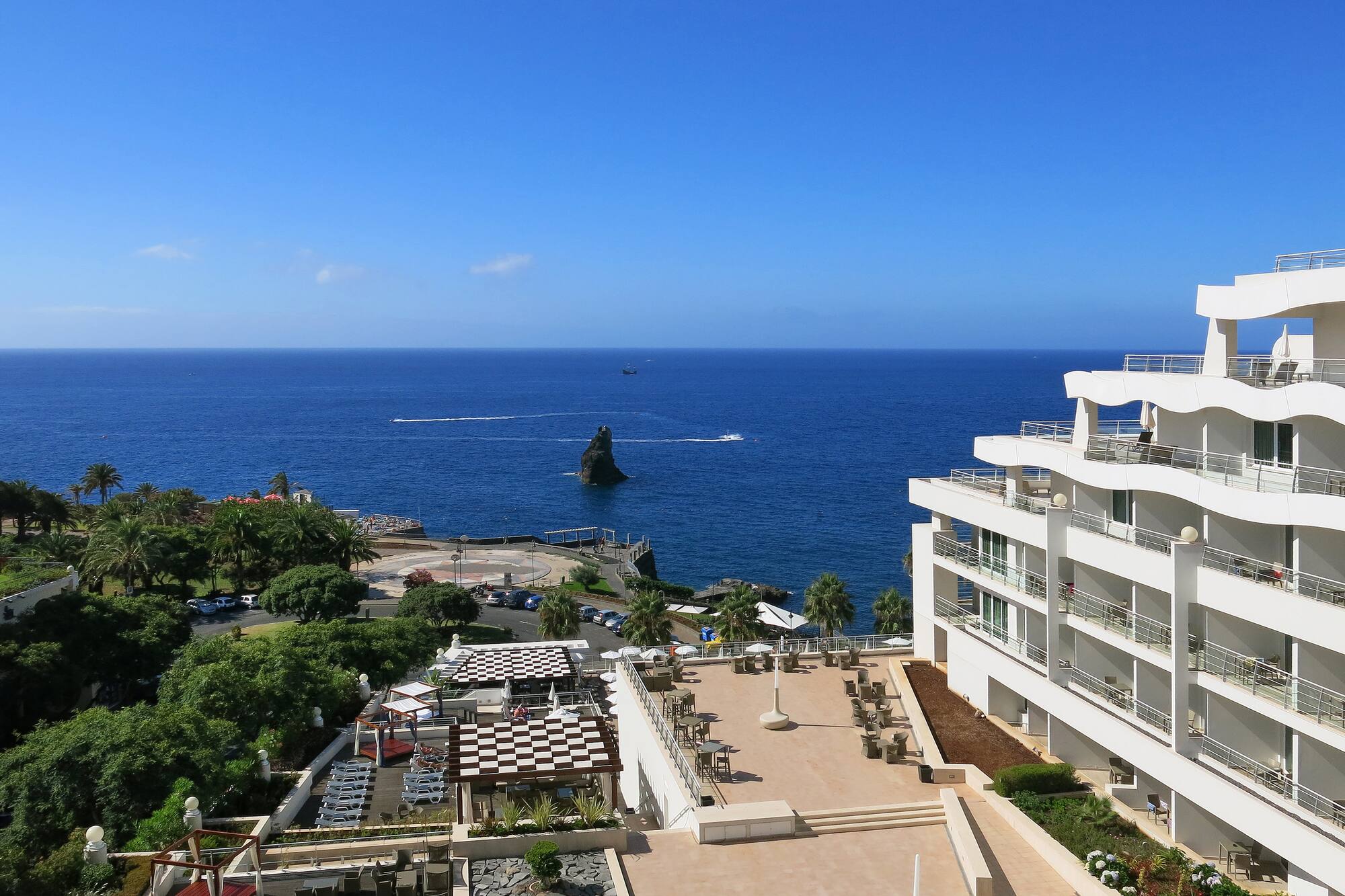 Oceanfront hotel resort with balconies, outdoor terraces, and blue sea.