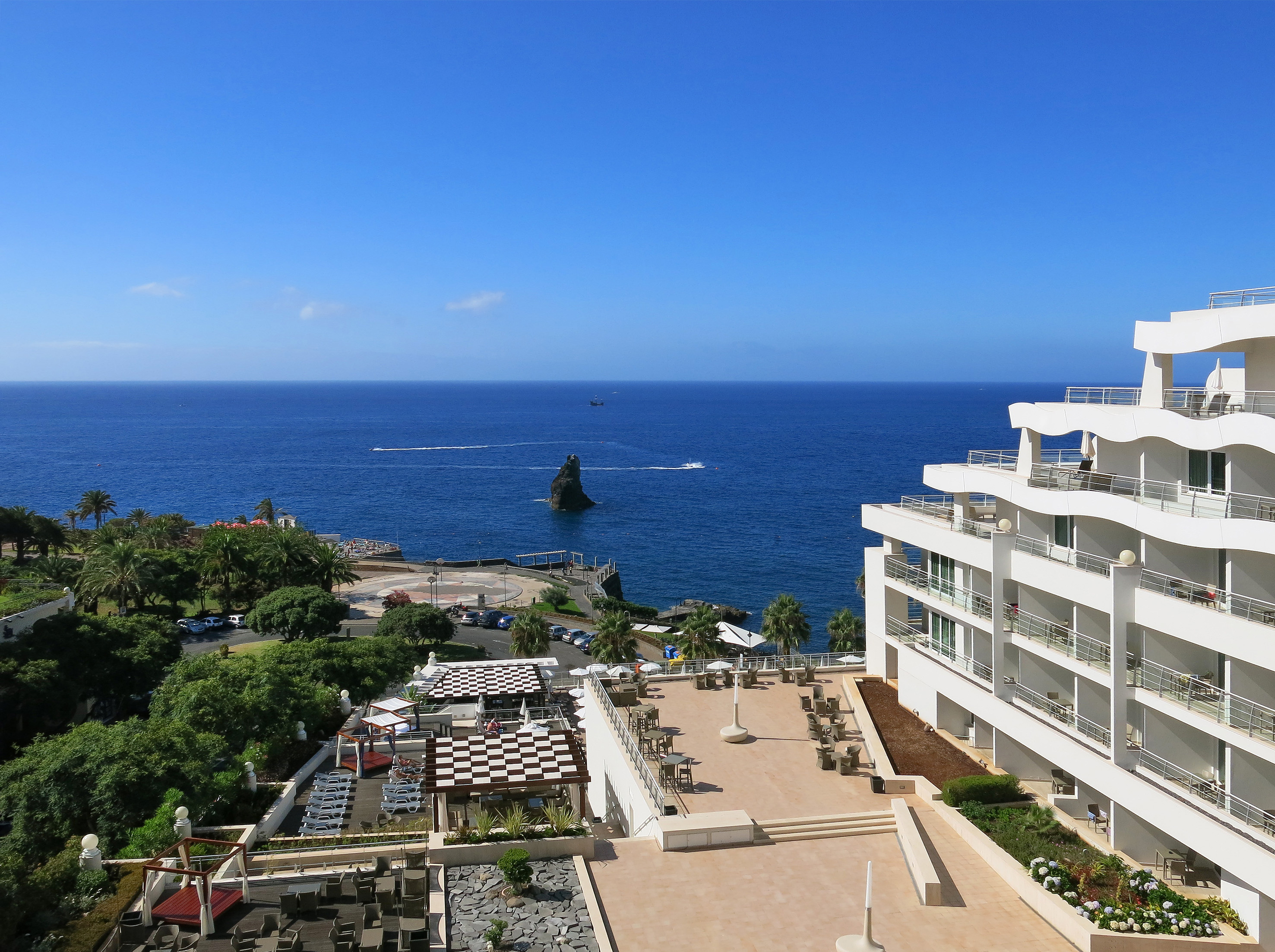 Oceanfront hotel resort with balconies, outdoor terraces, and blue sea.