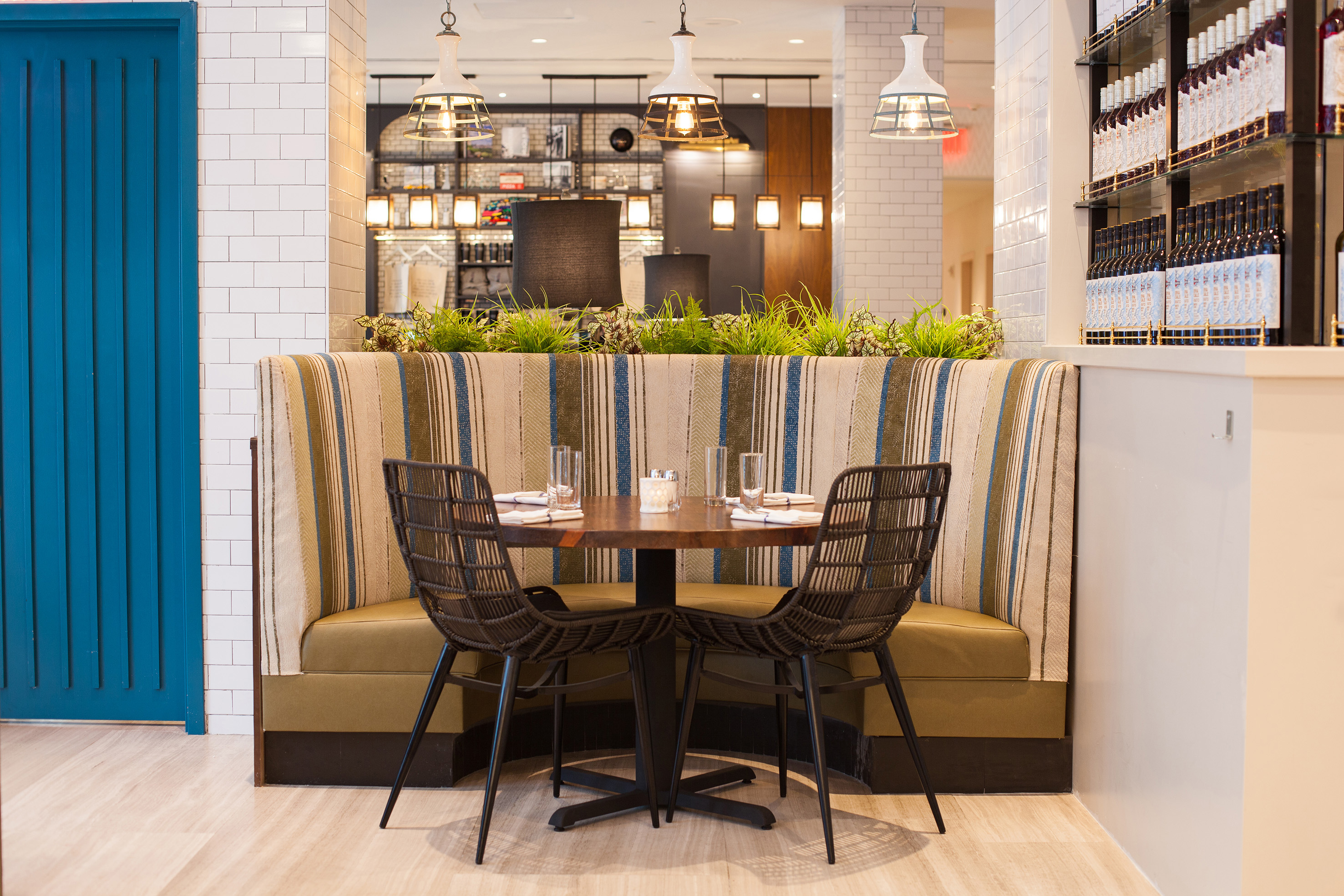 Modern restaurant booth, striped fabric, round table for two, bar area.