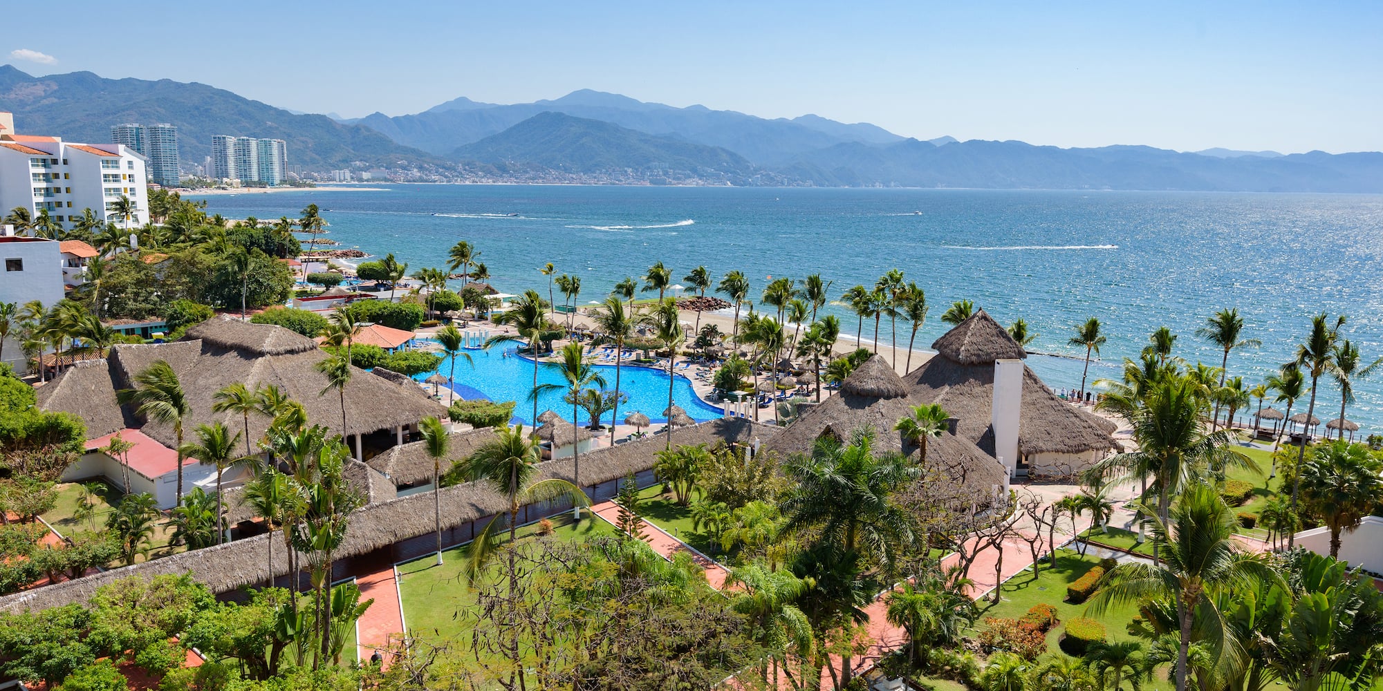 a resort with a pool and palm trees by the water