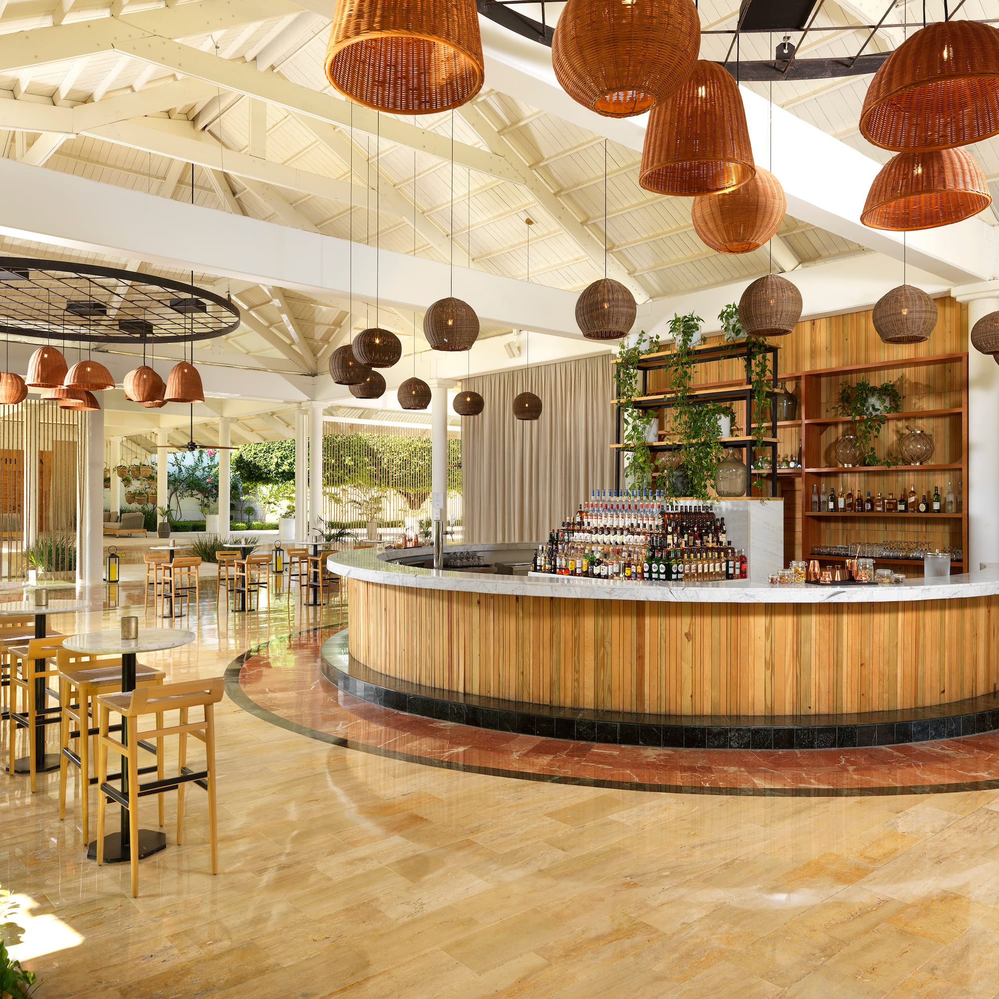 Tropical resort bar with wood counter, rattan lights, and lounge seating.