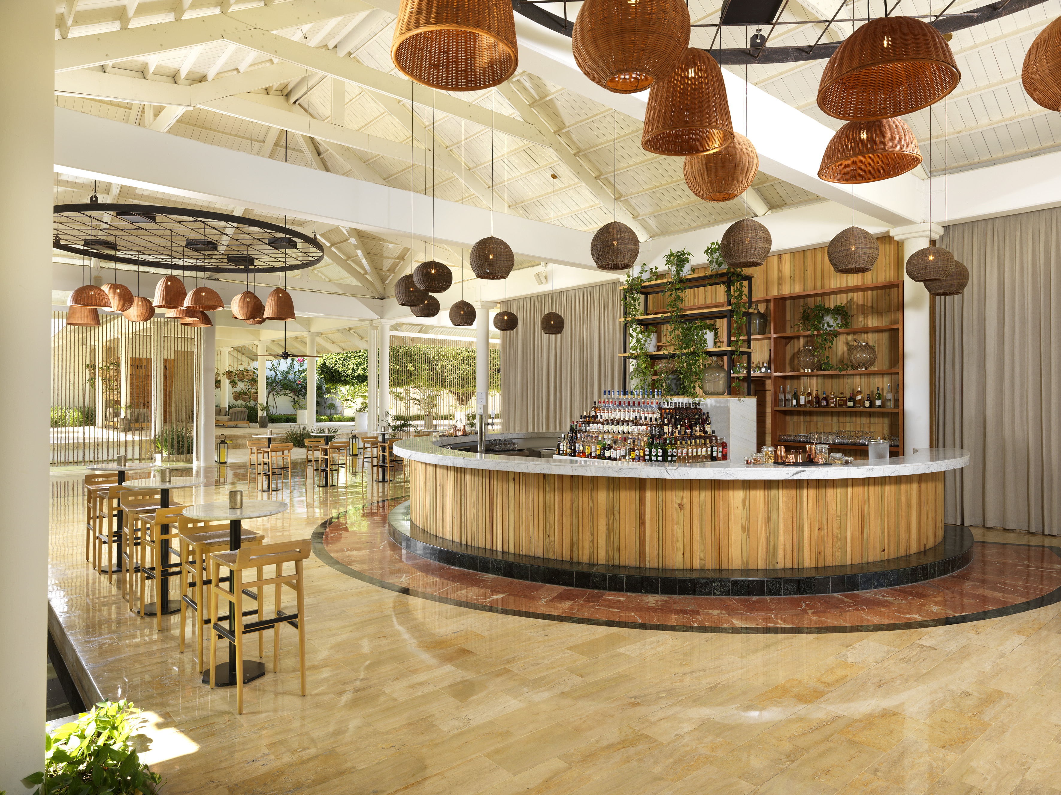 Tropical resort bar with wood counter, rattan lights, and lounge seating.