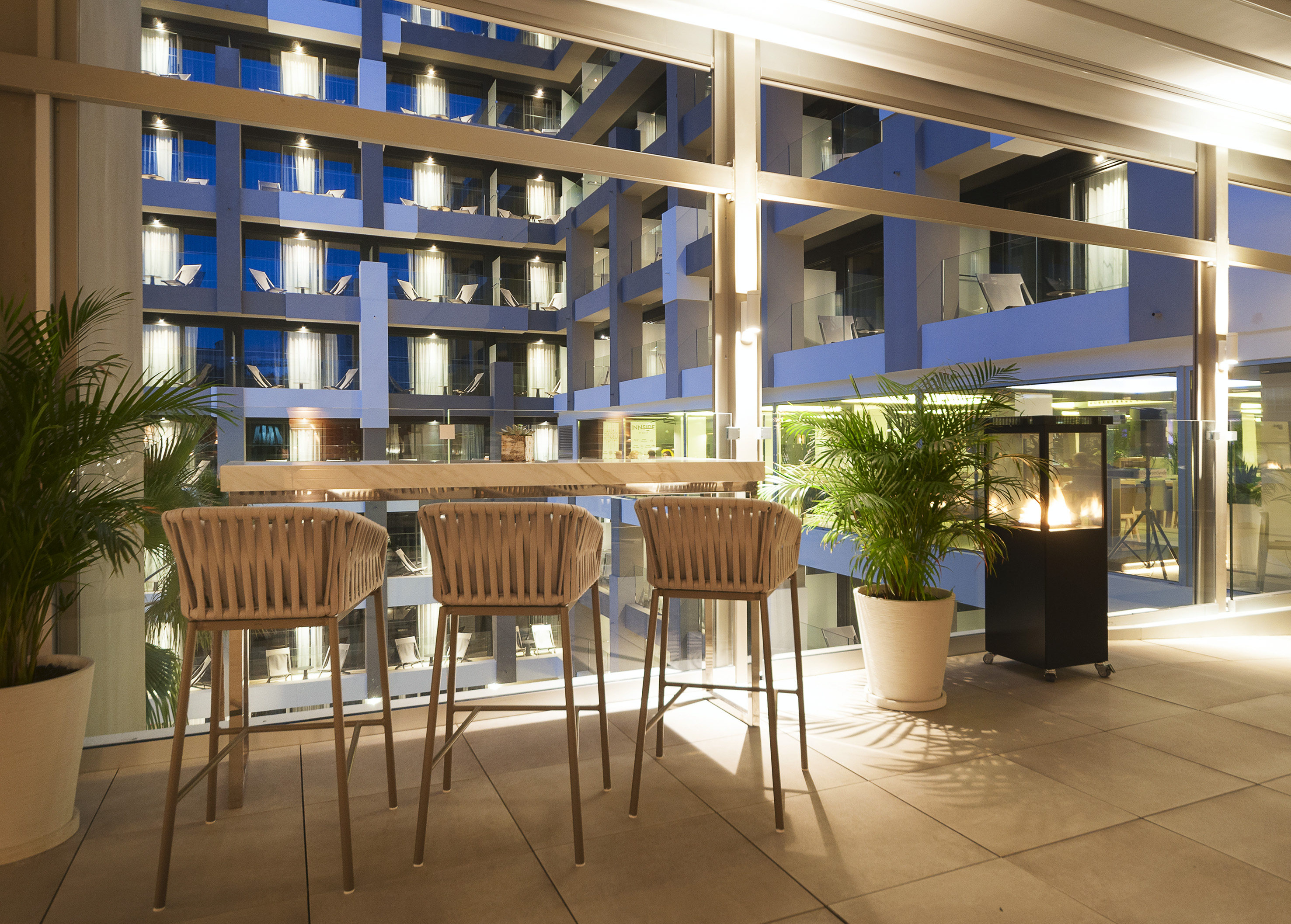 Modern hotel outdoor bar terrace at night, elegant design, urban view.