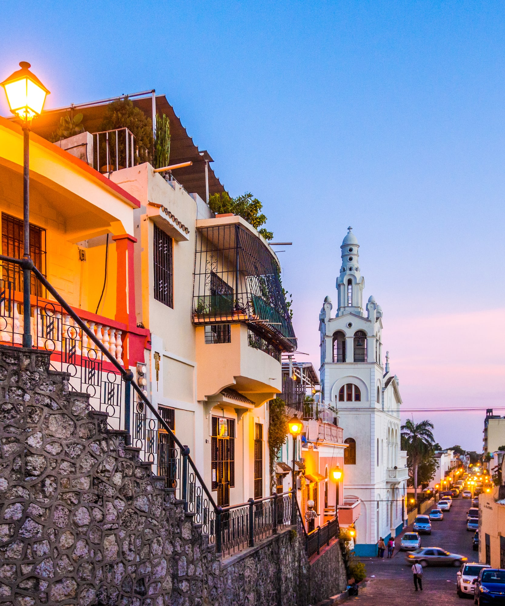 Calle colonial de Santo Domingo al anochecer, con casas coloridas e iglesia.