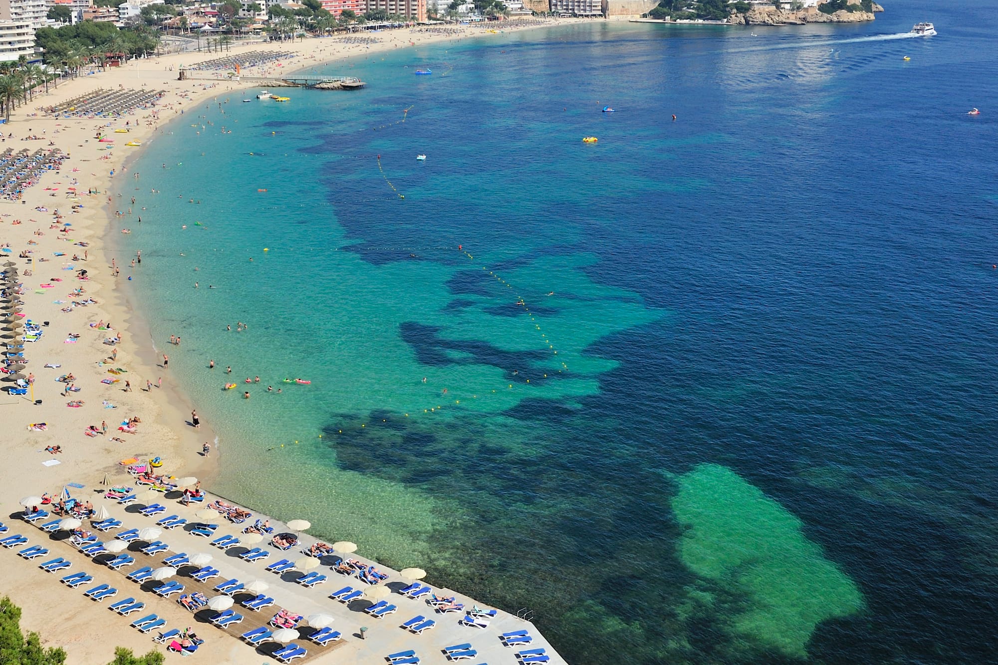 a beach with many people and a city in the background