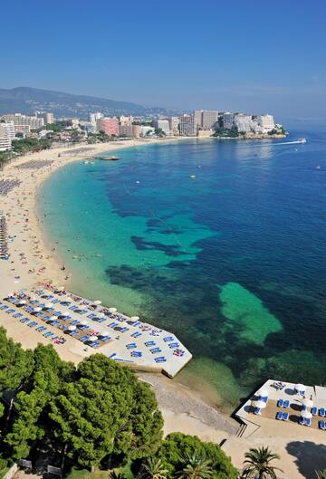 a beach with many people and a city in the background