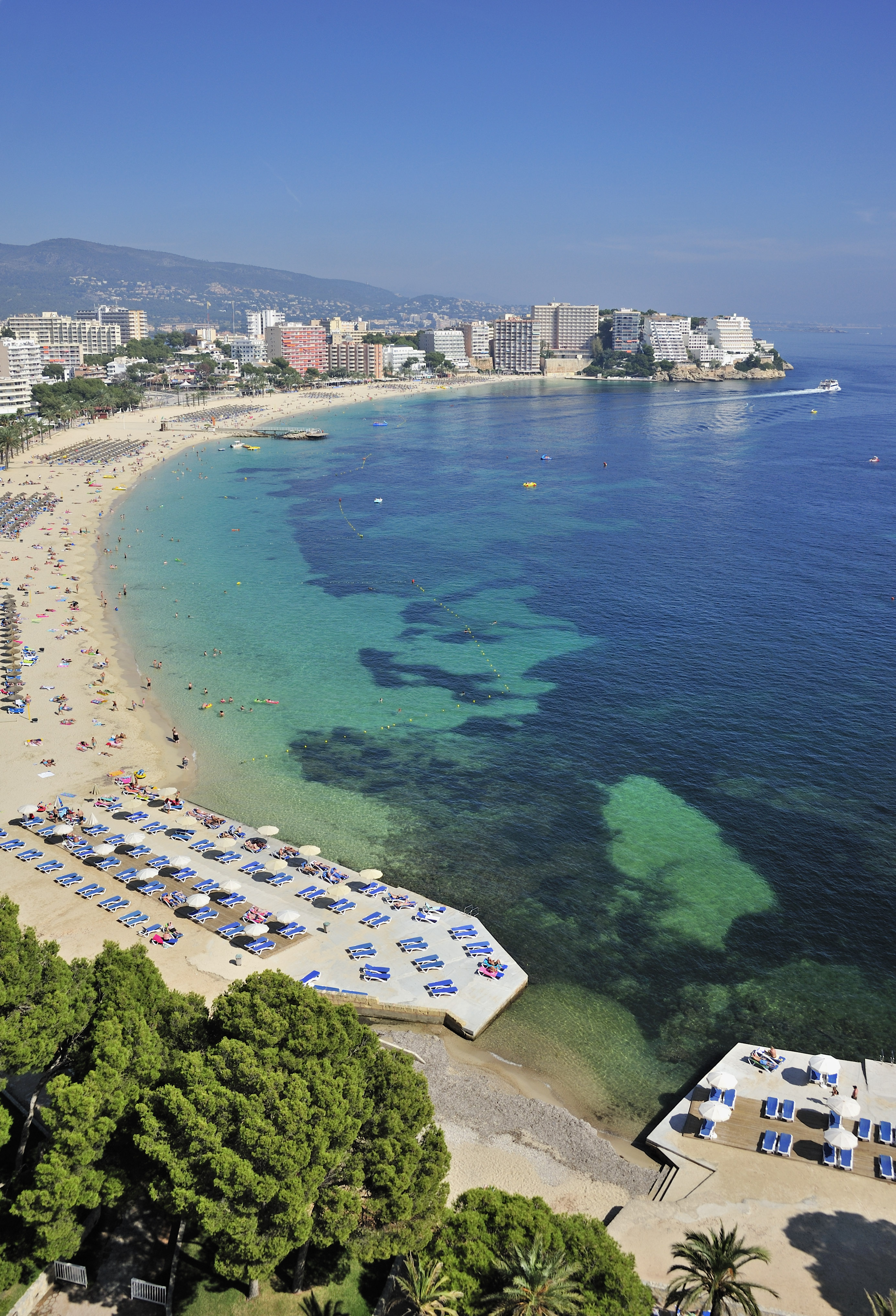 a beach with many people and a city in the background