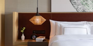 a bed with a lamp and a book on a table