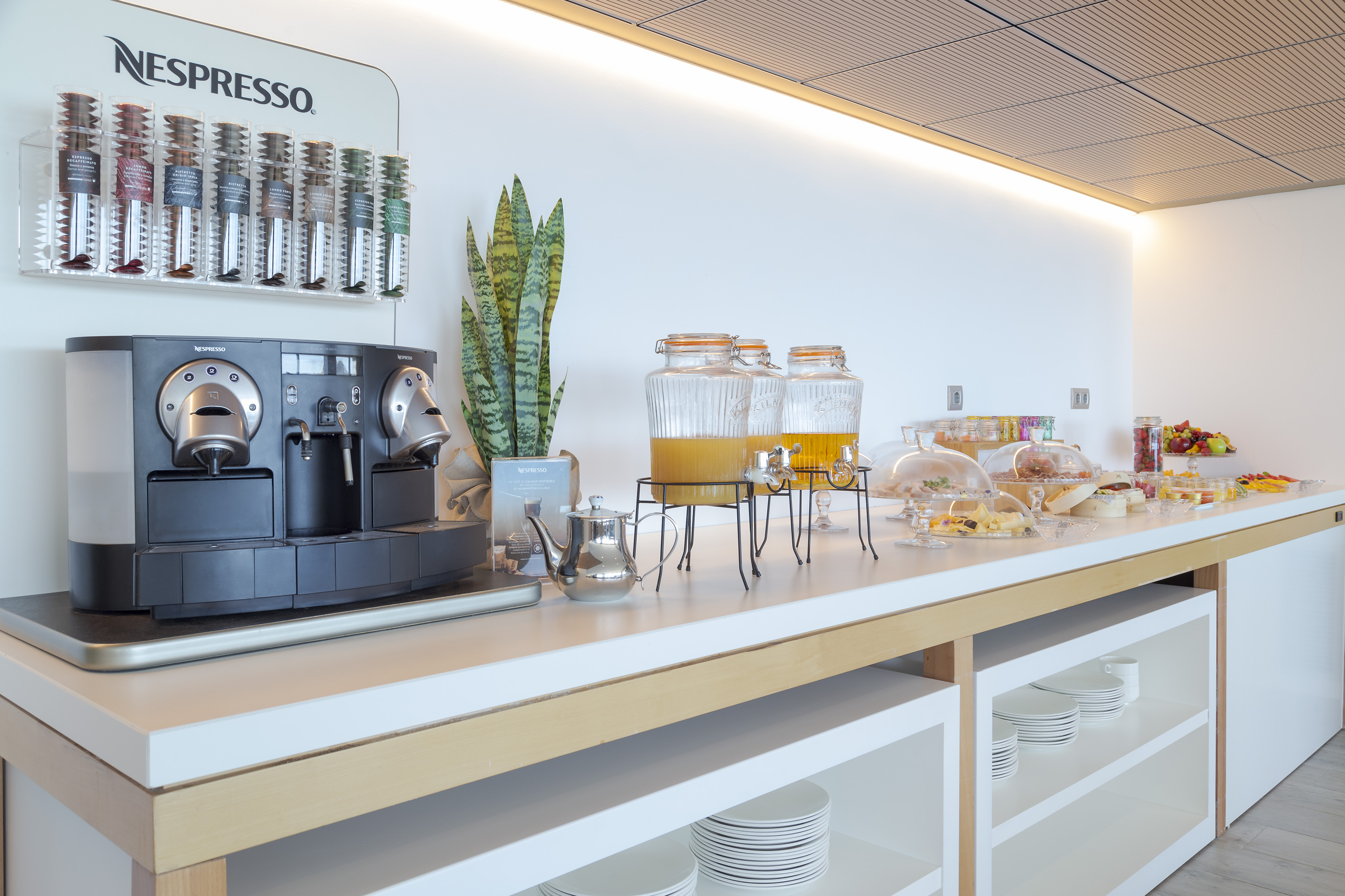 Nespresso coffee station, juice, pastries, and fruit at a breakfast buffet.