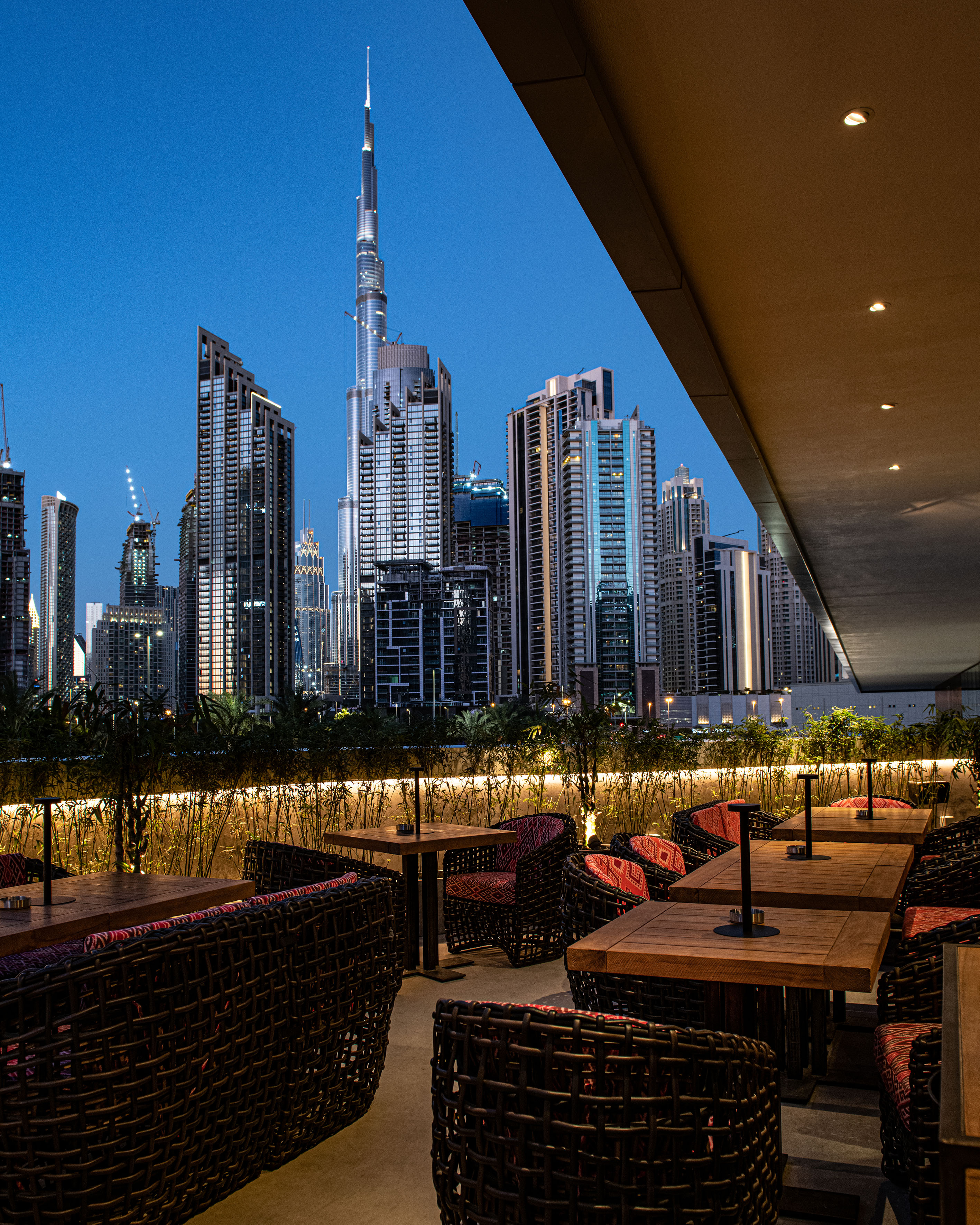 Outdoor restaurant patio with Dubai skyline and Burj Khalifa at dusk.