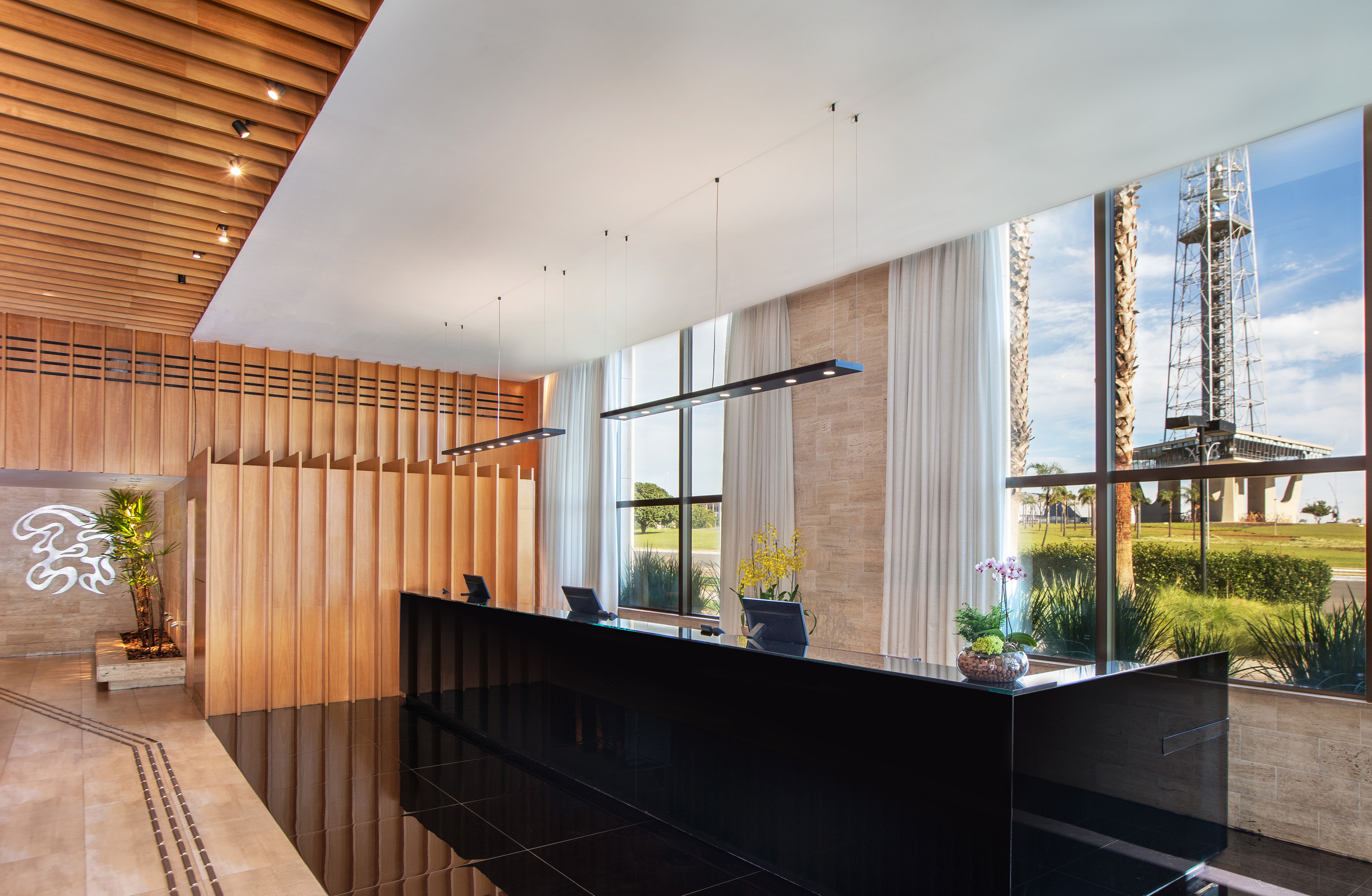 Modern hotel reception with black desk, wood paneling, and large windows. - Hotel Brasil 21 Convention Affiliated by Meliá, Brasilia