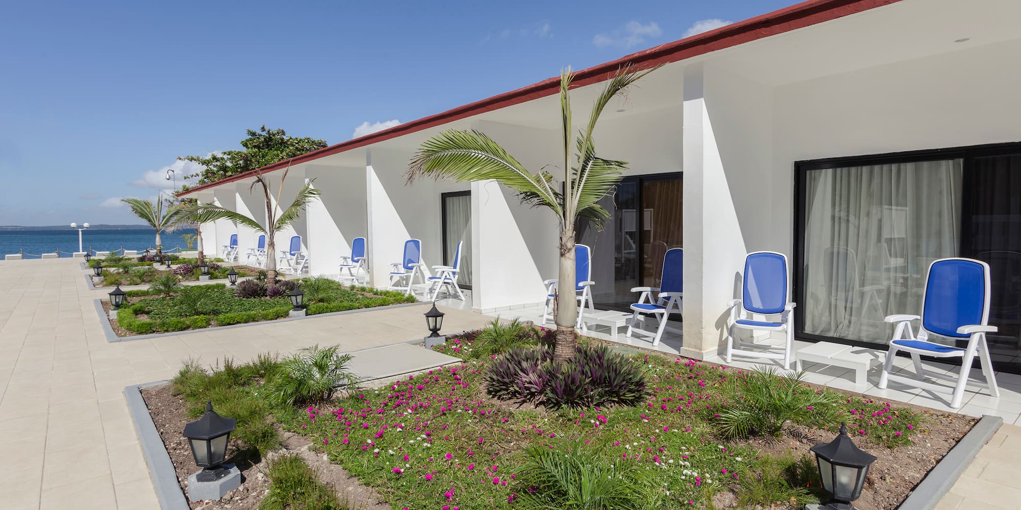 a white building with blue chairs and a garden