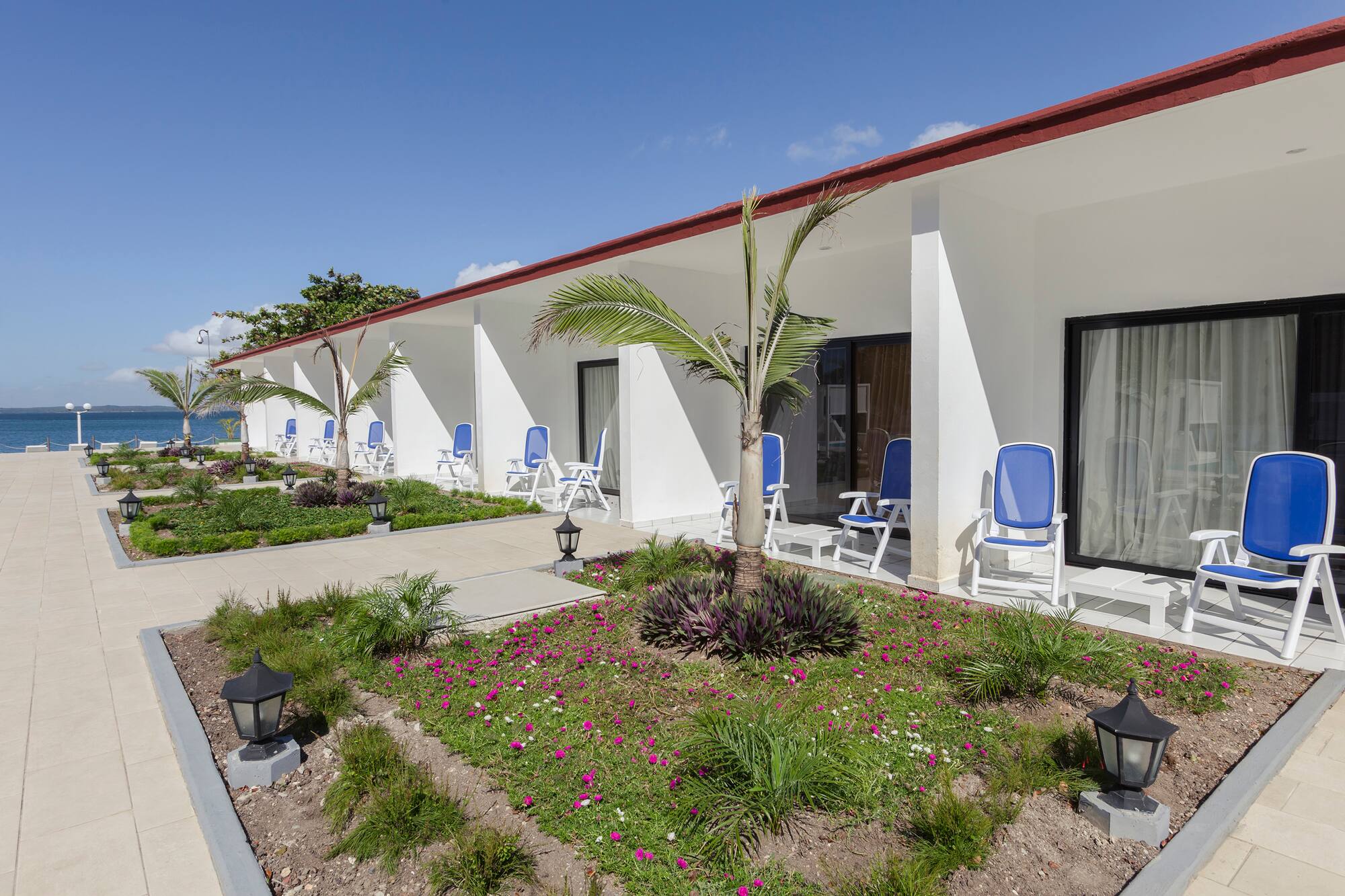 a white building with blue chairs and a garden