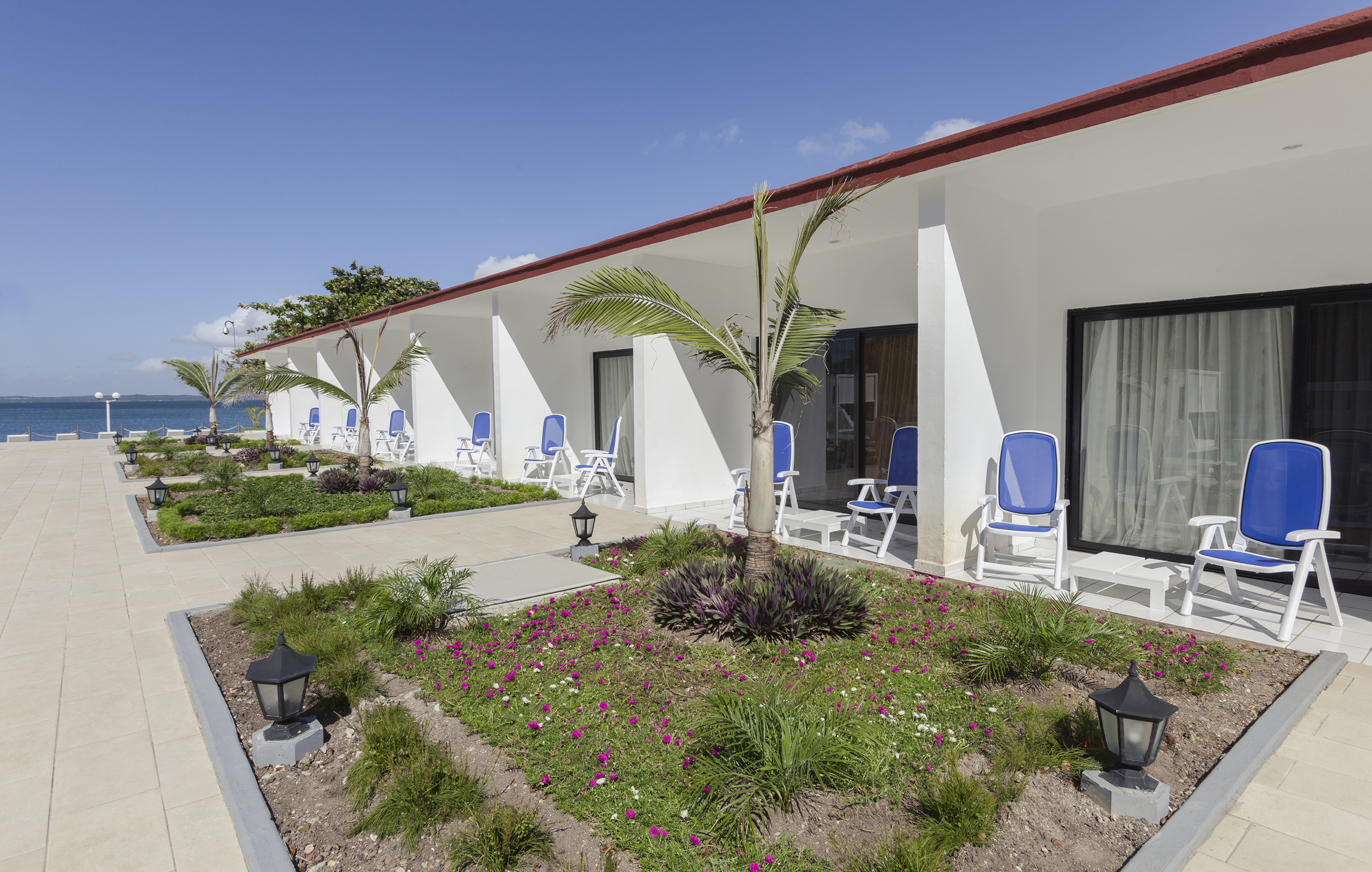 a white building with blue chairs and a garden