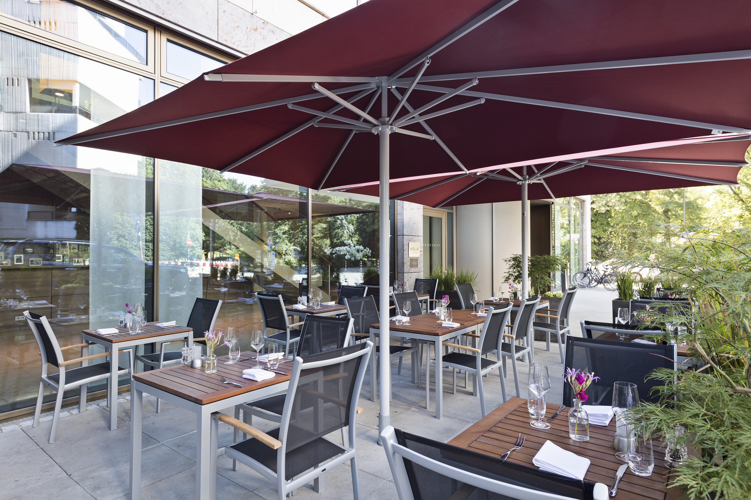 tables outside a restaurant with a red umbrella