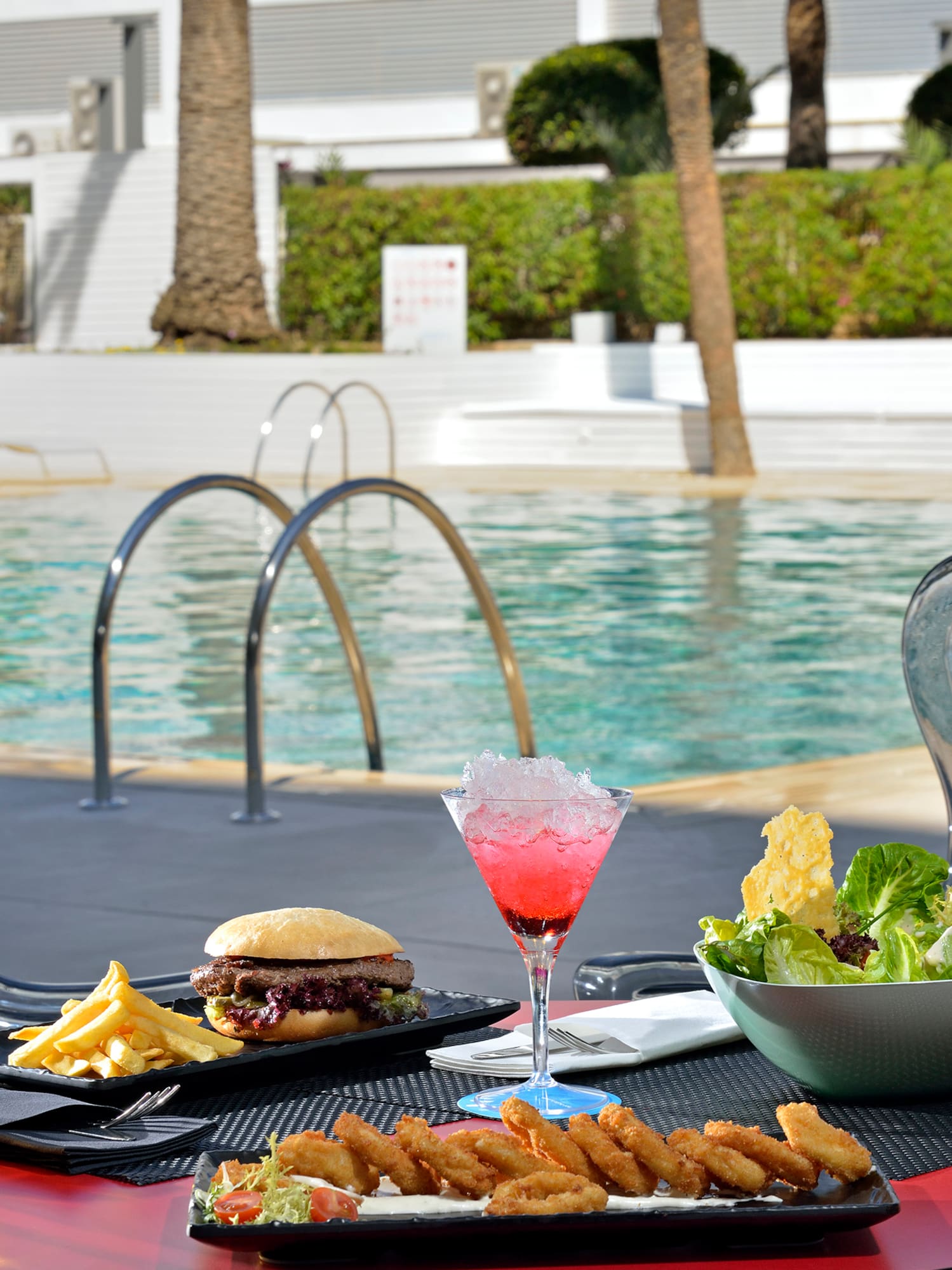 a table with food and drinks on it by a pool