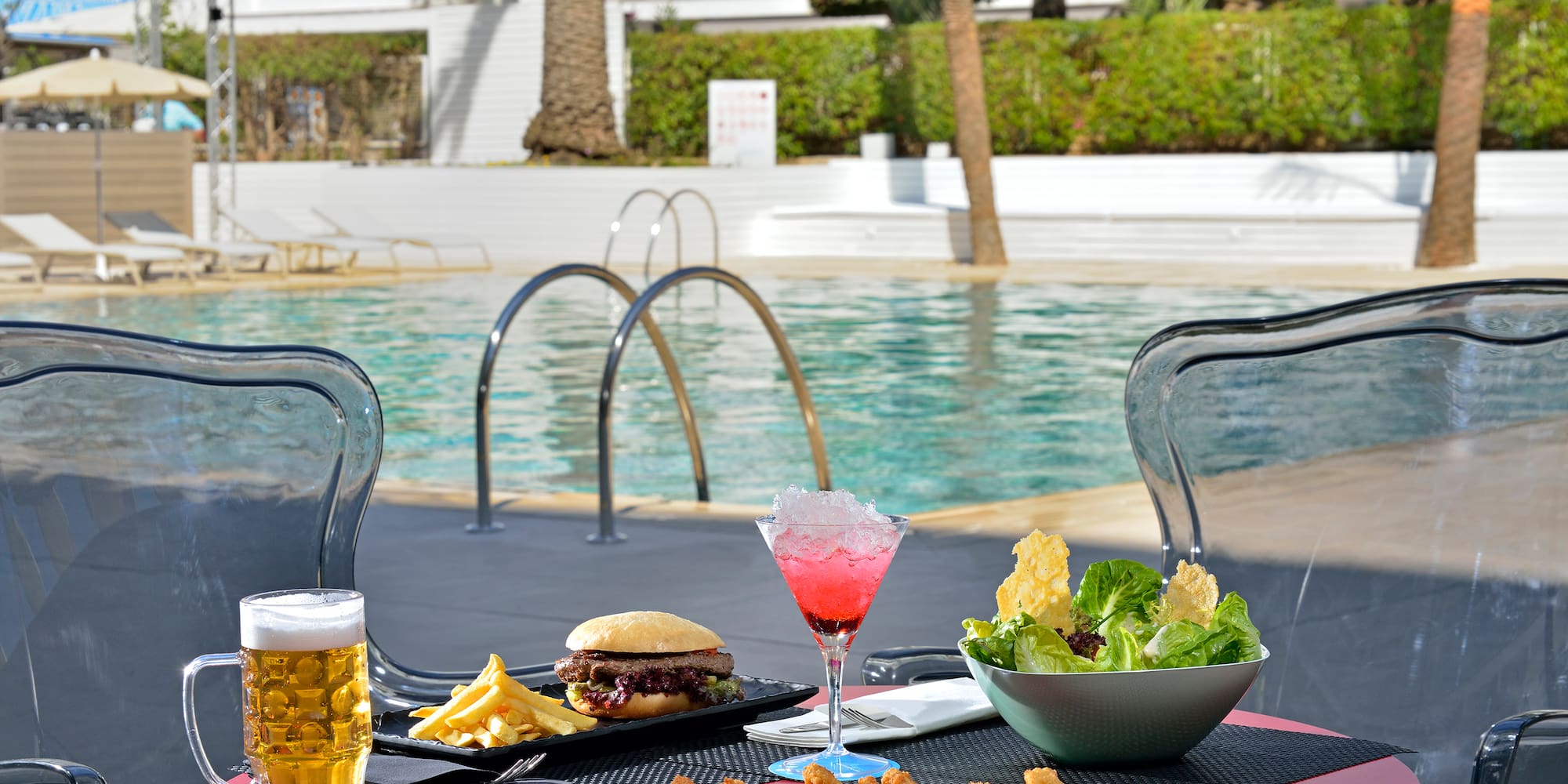 a table with food and drinks on it by a pool