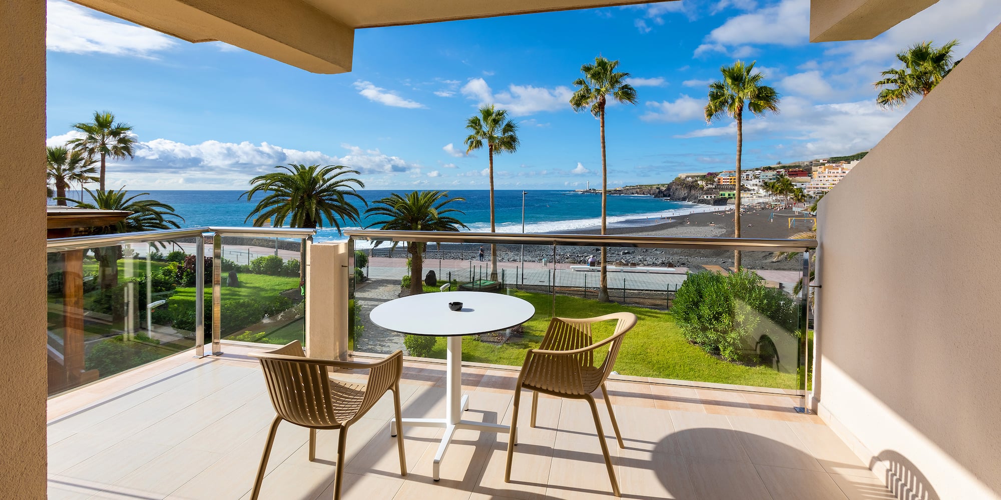 a balcony with chairs and a table overlooking the ocean