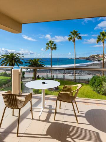 a balcony with chairs and a table overlooking the ocean